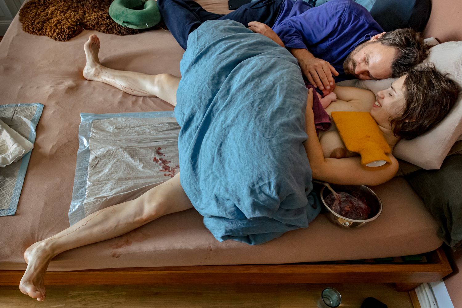 Eltern ruhen erschöpft und glücklich zusammen nach der Hausgeburt – stille Momente der Wochenbettfotografie Lübeck, Sylvia Fischer Foto