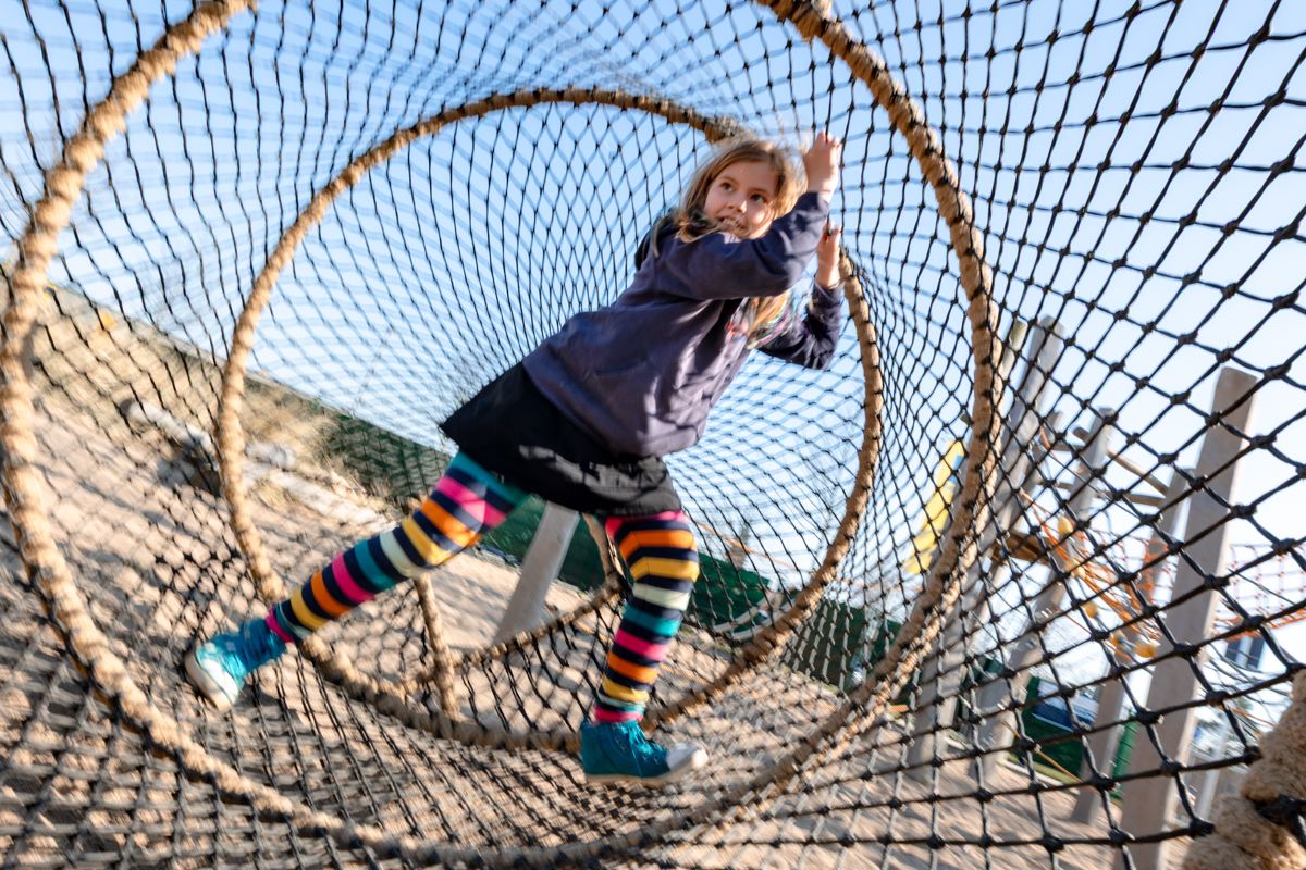 Kind in einem Netz auf einem Spielplatz an der Ostsee