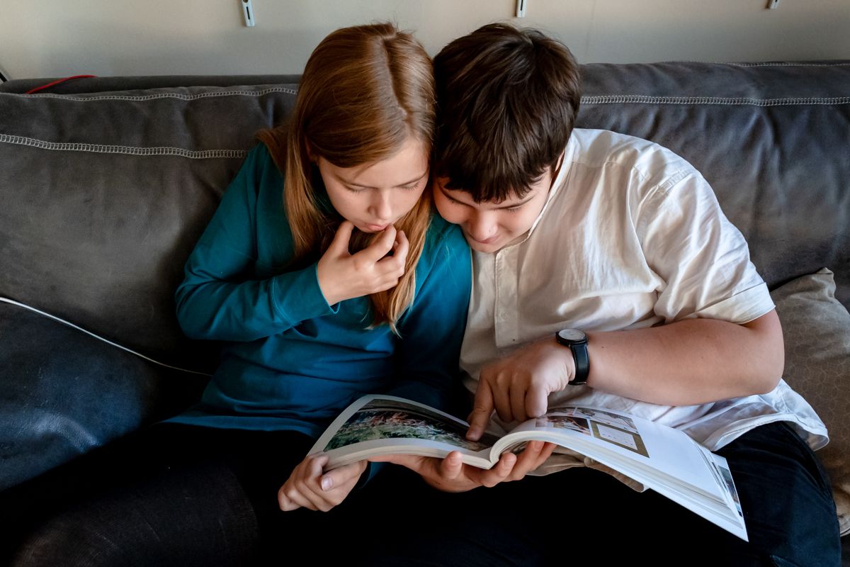 Kinder schauen sich ein Fotoalbum an - echter Moment im Familienalltag