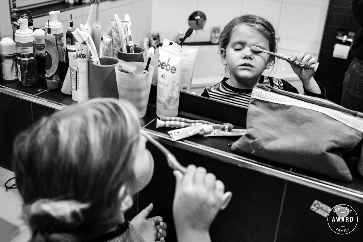 Kind putzt ernsthaft Augenlied mit der Zahnbürste vor dem Spiegel – Fearless Award, dokumentarische Familienfotografie Lübeck