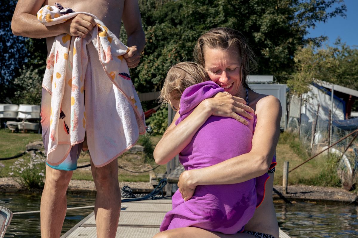 Mama trocknet Kind ab, Papa steht mit Handtuch dahinter - Familienshooting an der Ostsee
