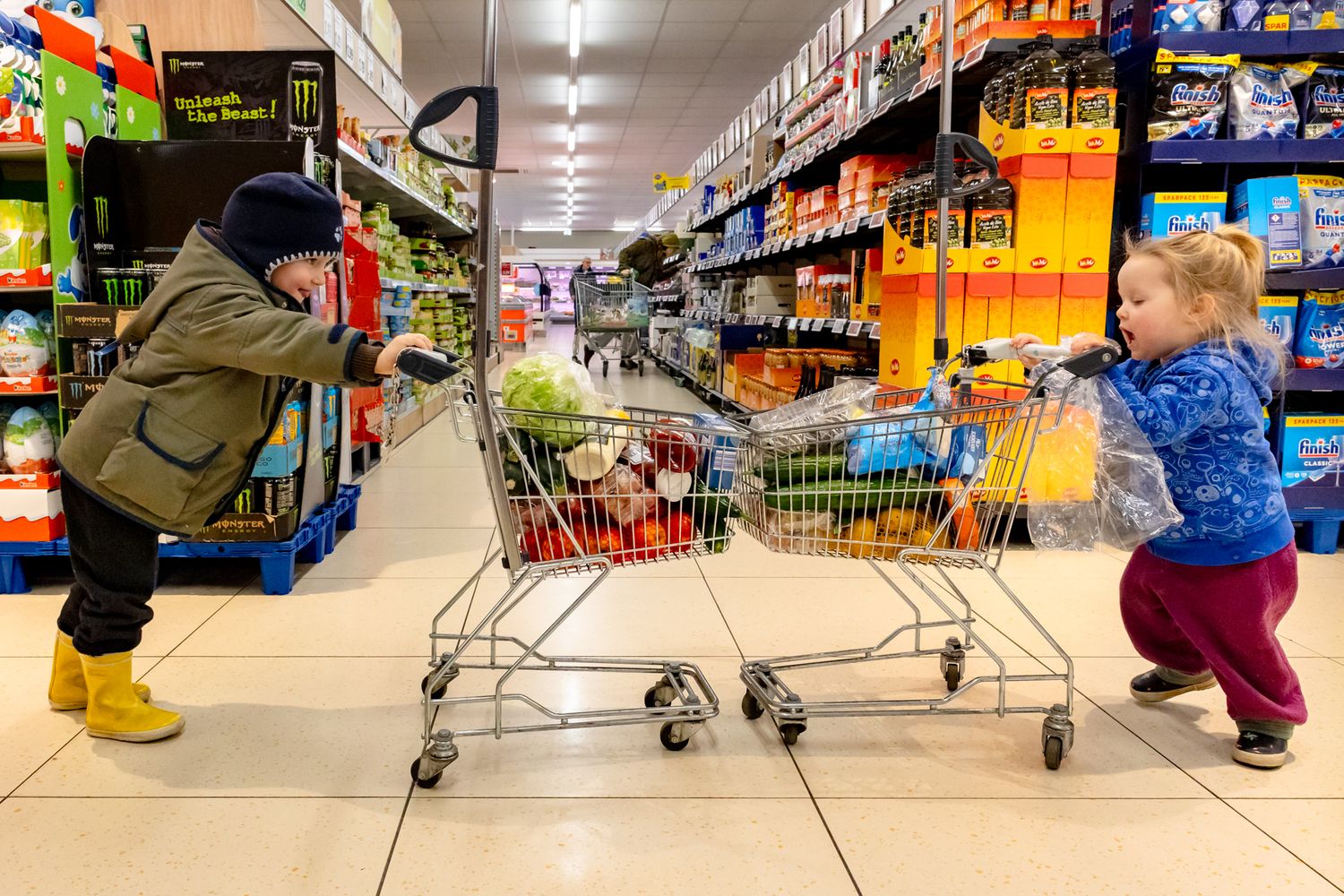 Zwei Kinder fahren mit Einkaufswagen im Supermarkt gegeneinander – Fearless Award, Familienreportage Lübeck