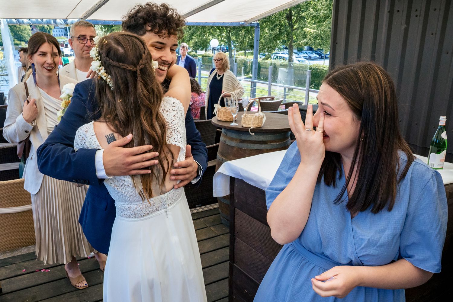 Brautpaar umarmt sich auf dem Schiff, gerührte Gäste im Hintergrund – emotionale Hochzeitsreportage Lübeck, Sylvia Fischer Fotografie