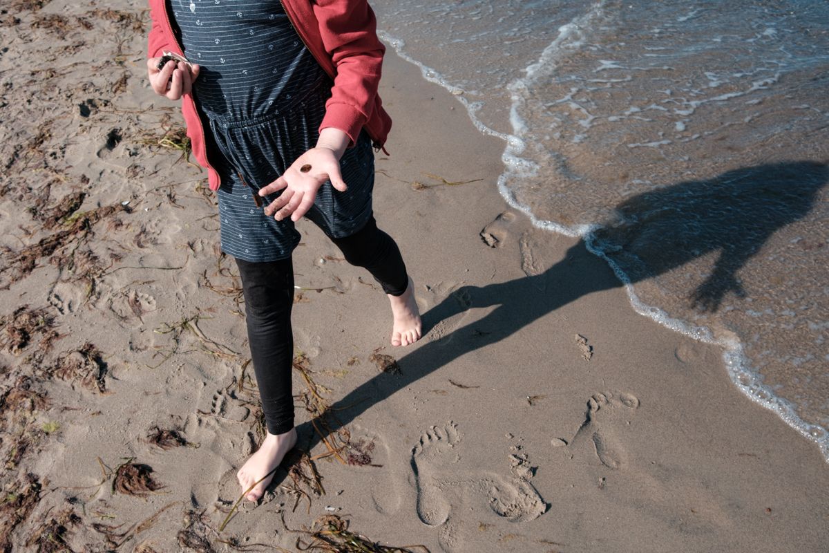 Kind mit Stein oder Muschel in der Hand am Strand an der Ostsee