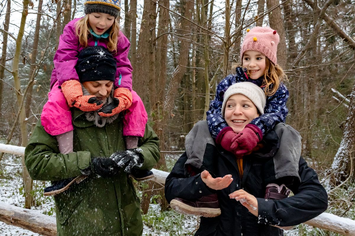 Familie spielt im Schnee im Wald, Kinder auf den Schultern der Eltern – Familienshooting Ratzeburg im Winter