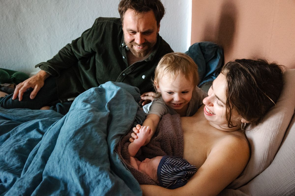Familie im Bett kurz nach der Geburt – Vater, Mutter, Geschwisterkind und Neugeborenes – Geburtsreportage Lübeck, Sylvia Fischer Fotografie
