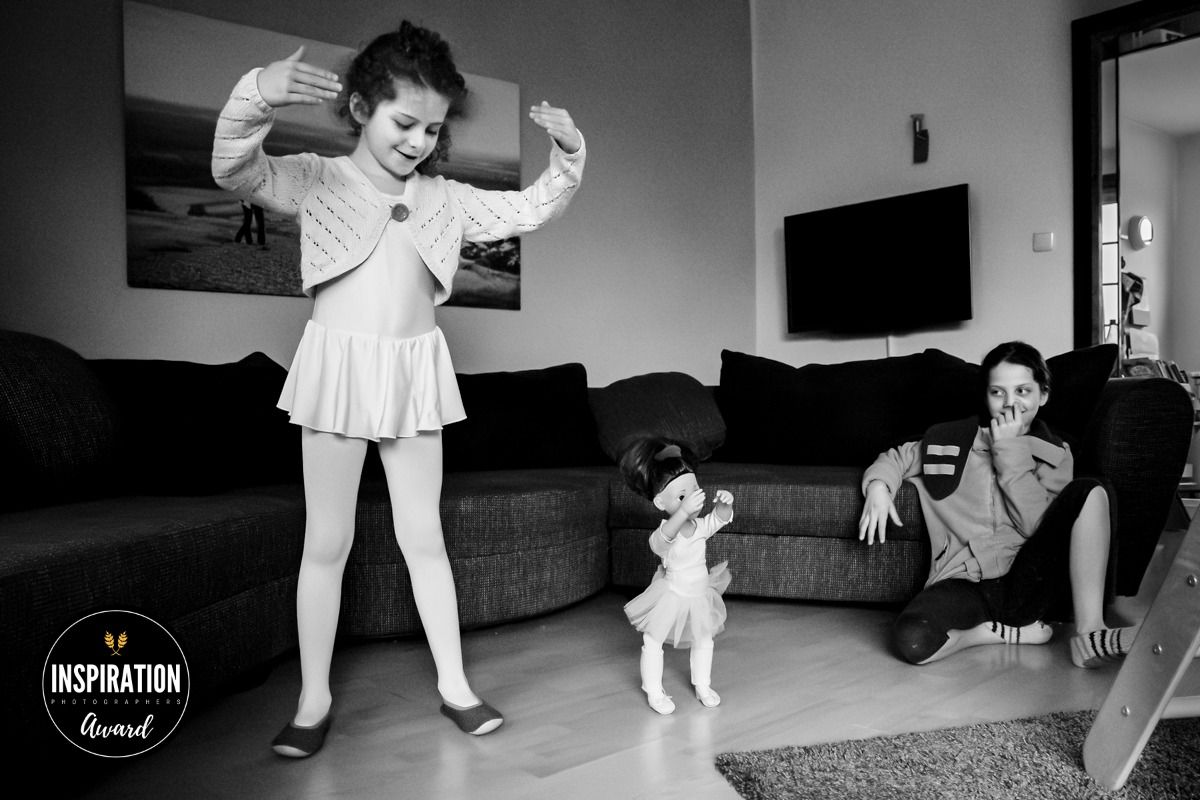Mädchen tanzt mit Puppe, Schwester lacht darüber – Inspiration Award, dokumentarische Familienfotografie Lübeck, Sylvia Fischer Fotografie