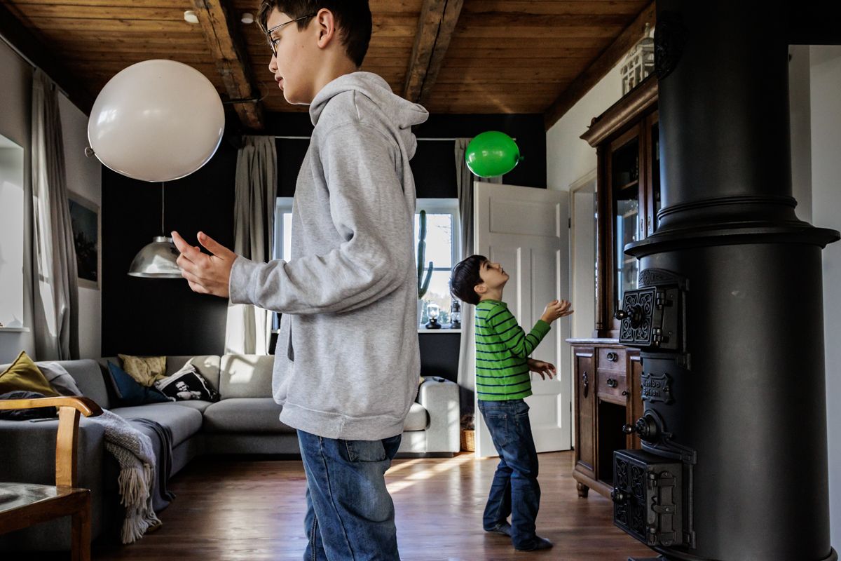 Zwei Geschwister spielen mit Luftballons im Wohnzimmer – ungestellter Familienalltag bei der Familienfotografie Lübeck