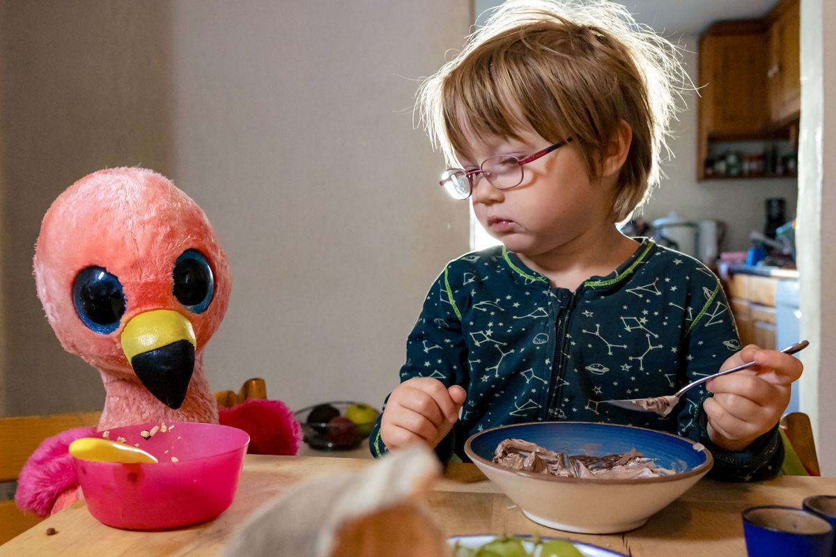Kind frühstückt ernsthaft neben einem pinken Flamingo-Kuscheltier – echter Alltagsmoment beim Familienshooting Lübeck