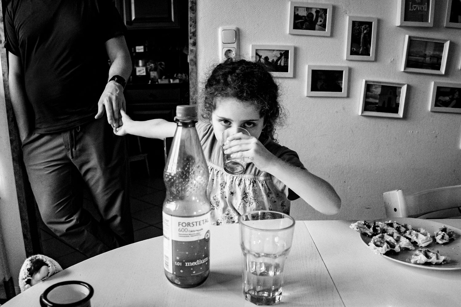Dokumentarische Familienfotografie Lübeck – Kind beim Frühstück, Familienfotos an der Wand
