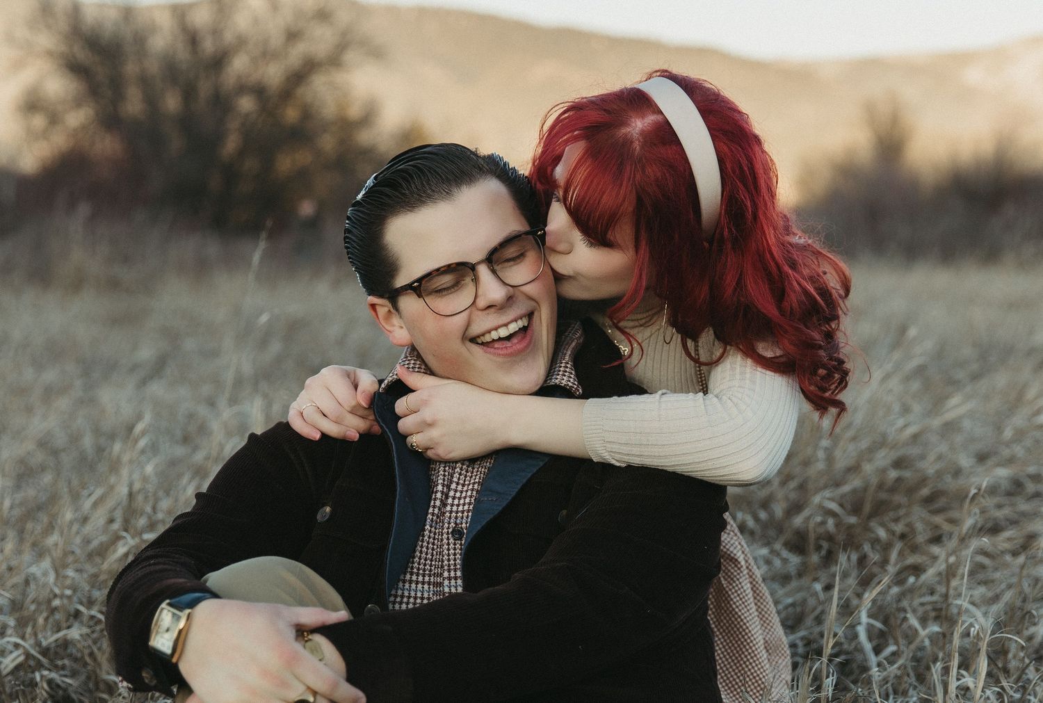 A couple shares tender moments together in a sunlit field during a romantic outdoor photo session.
