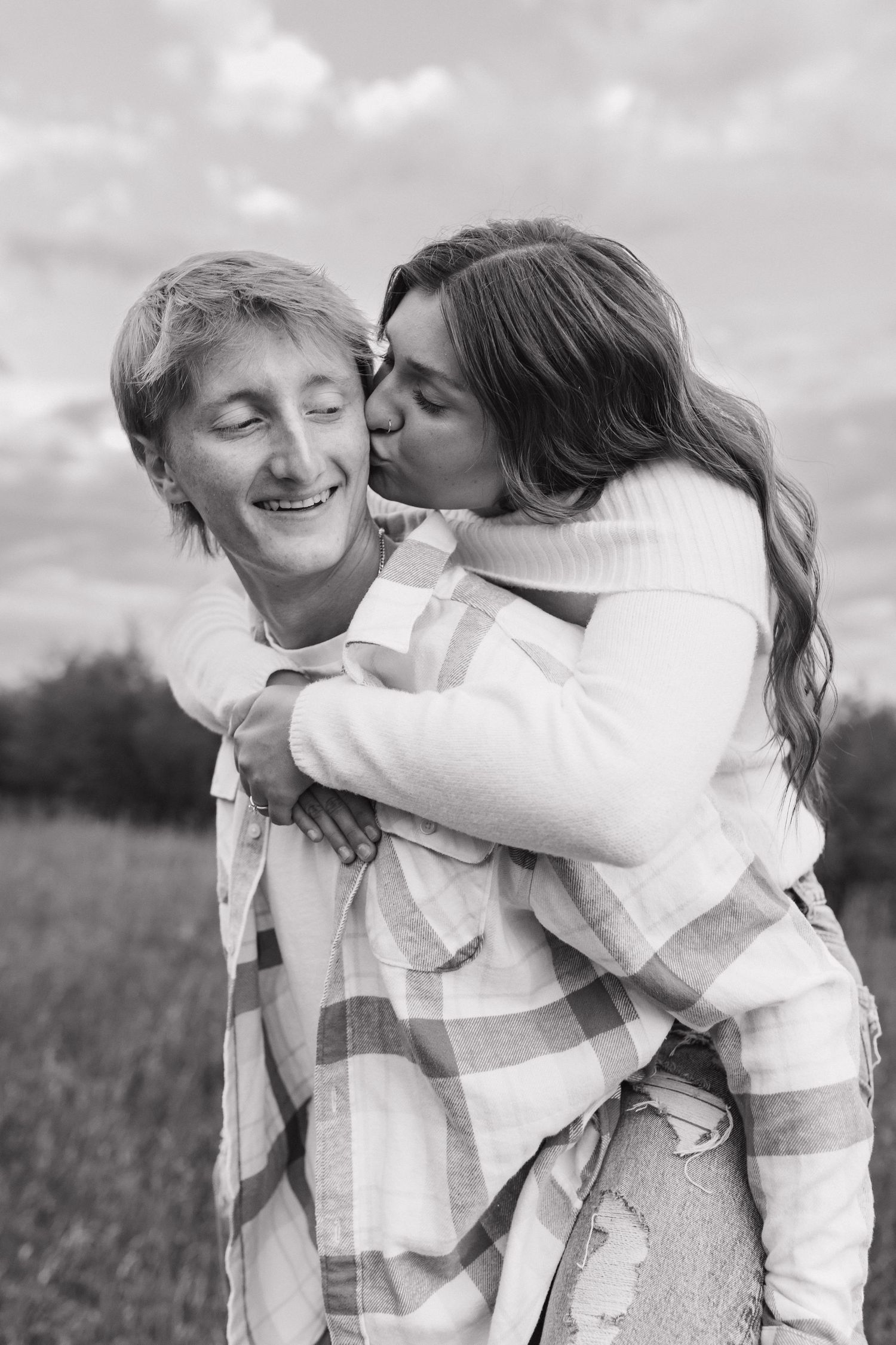 Black and white photo of playful couple in casual winter wear.