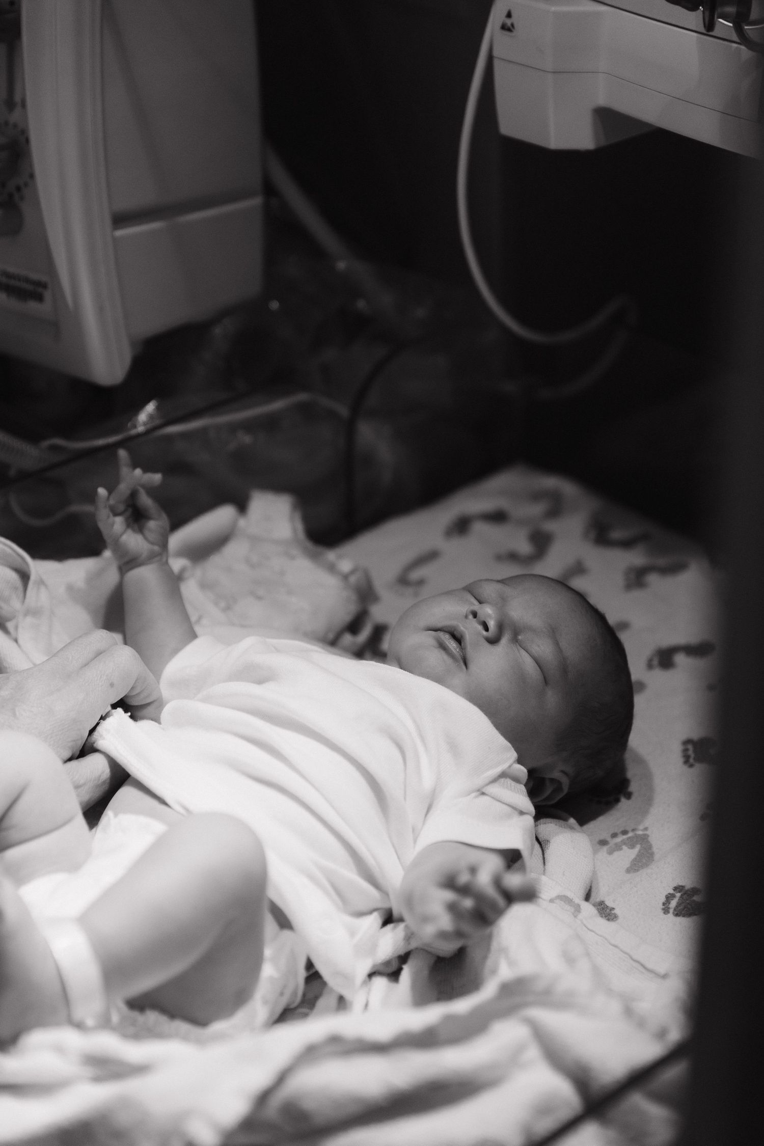 Black and white portrait of a newborn baby lying on hospital bedding.