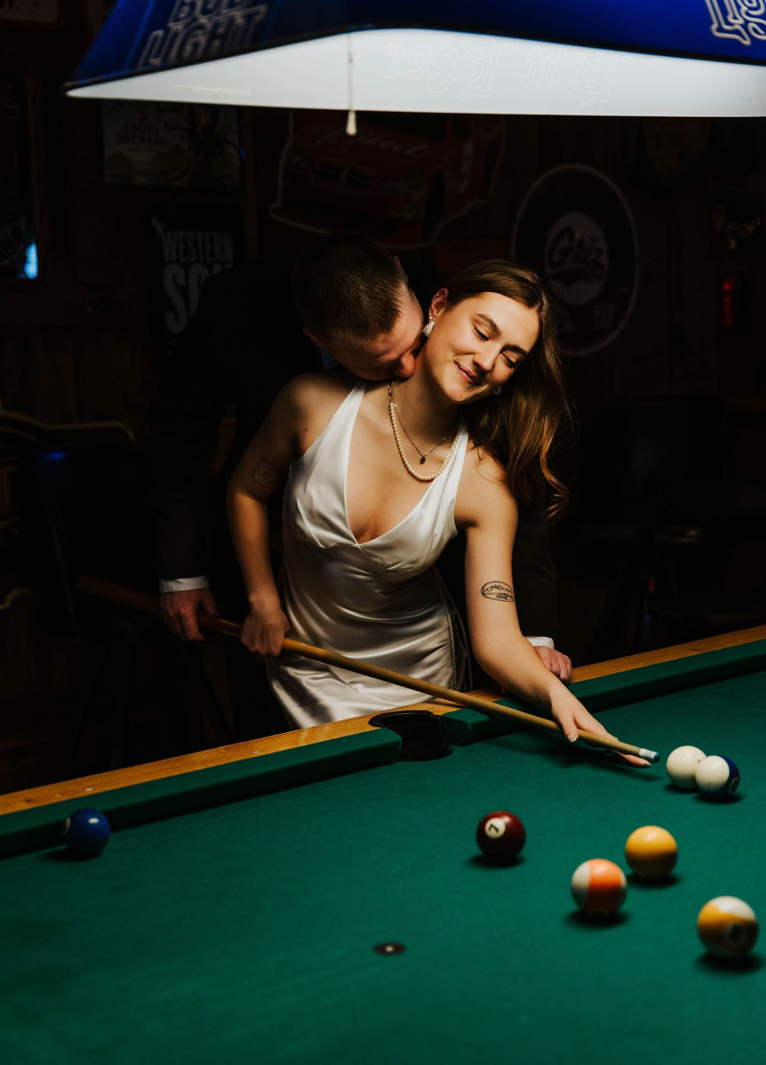 Couple sharing an intimate moment while playing pool under blue lighting.