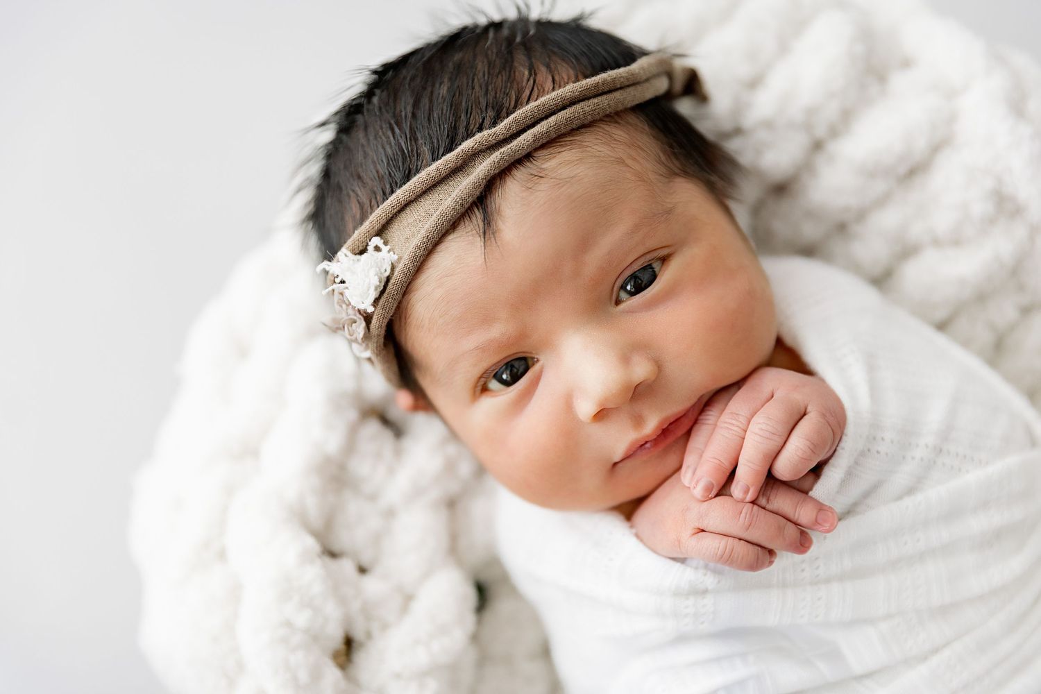 Newborn baby sleeping peacefully on soft white bedding in a series of close-up portraits.