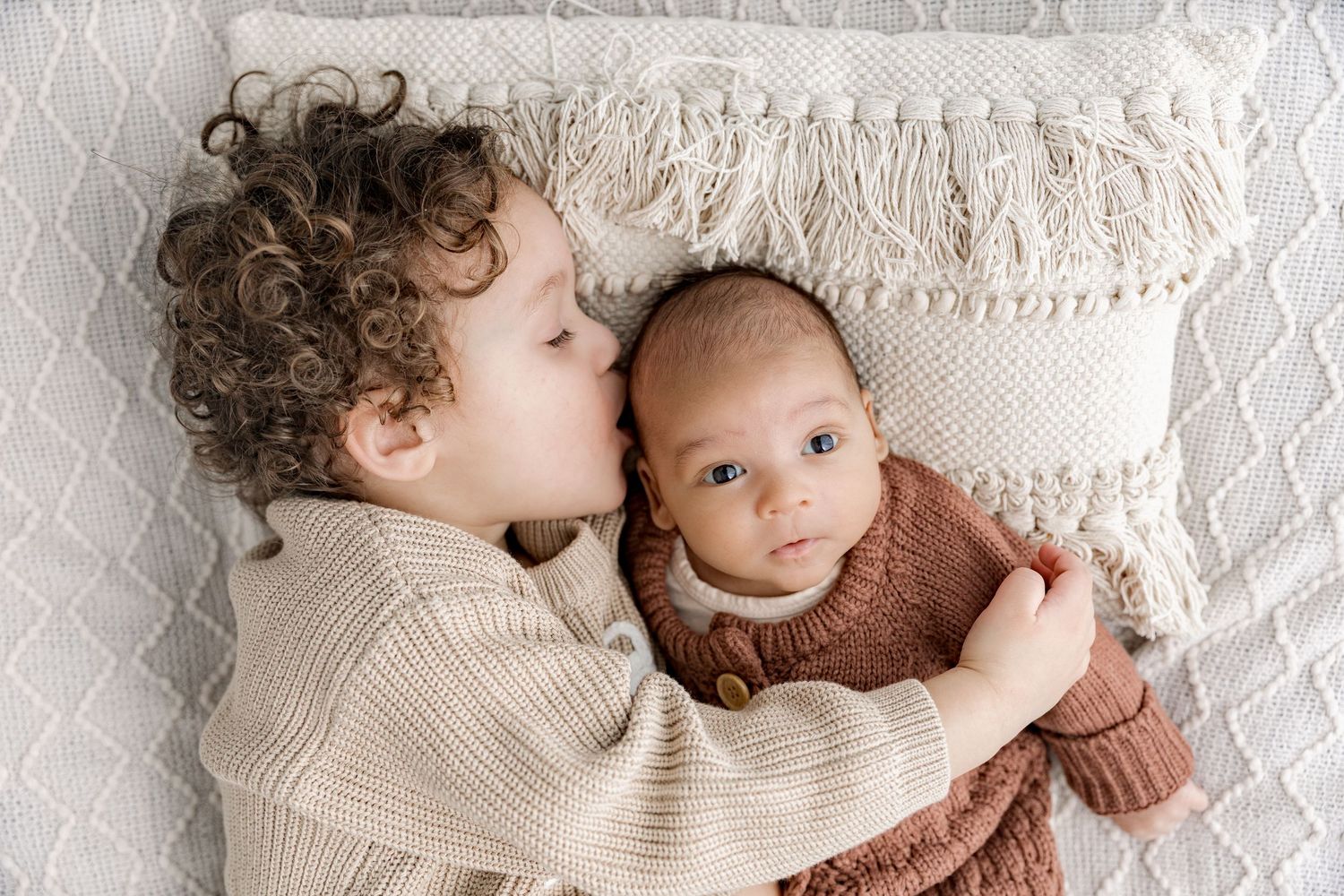 A collection of tender moments showing a parent and baby lying together on white textured bedding.