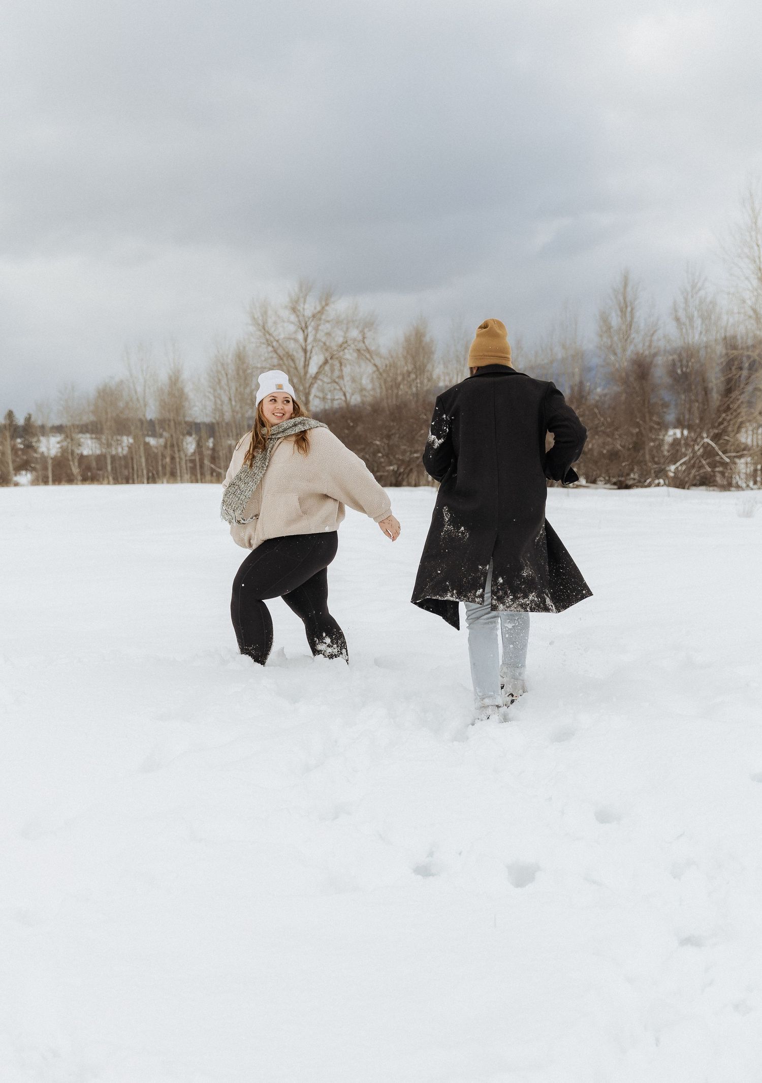 Two people running and playing together in a snowy winter landscape.