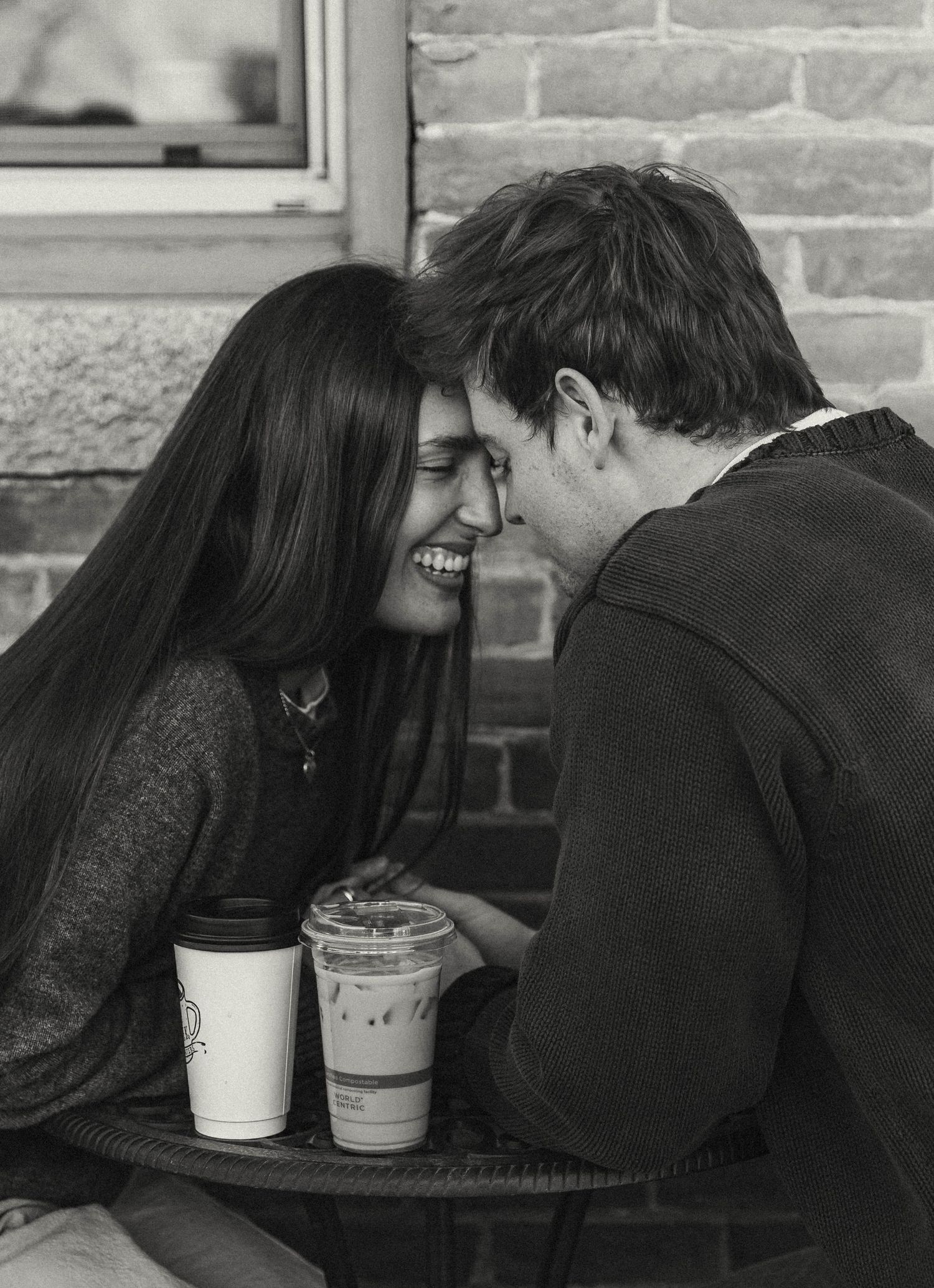Couple sharing intimate moment over coffee drinks at outdoor cafe table.
