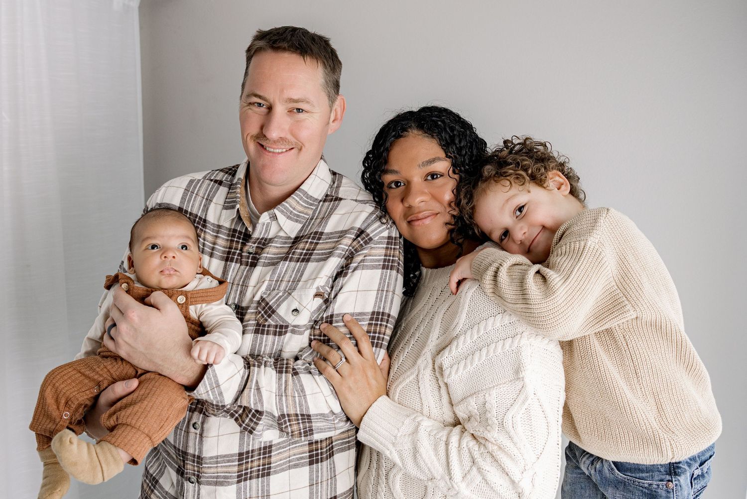 A family wearing coordinated neutral tones poses together for a series of casual lifestyle portraits.