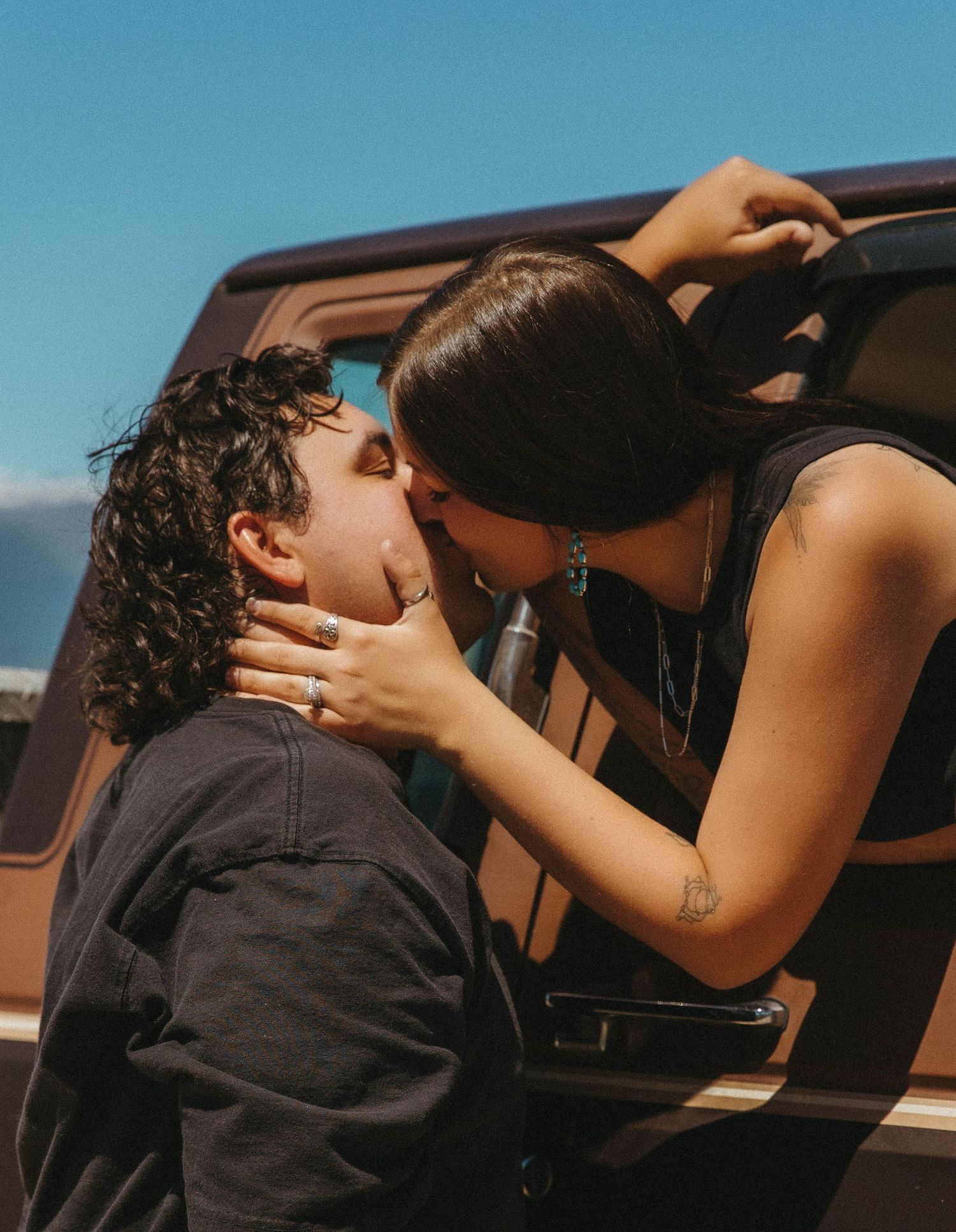 Sequence of intimate moments between a couple in a parked car against a blue sky backdrop.