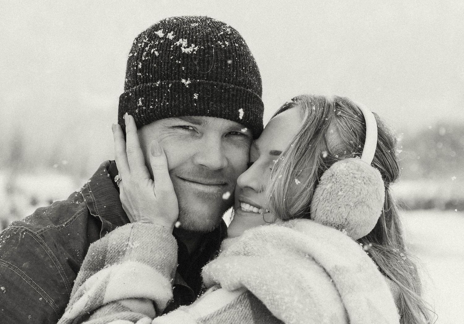An intimate black and white portrait of a couple wearing winter accessories.