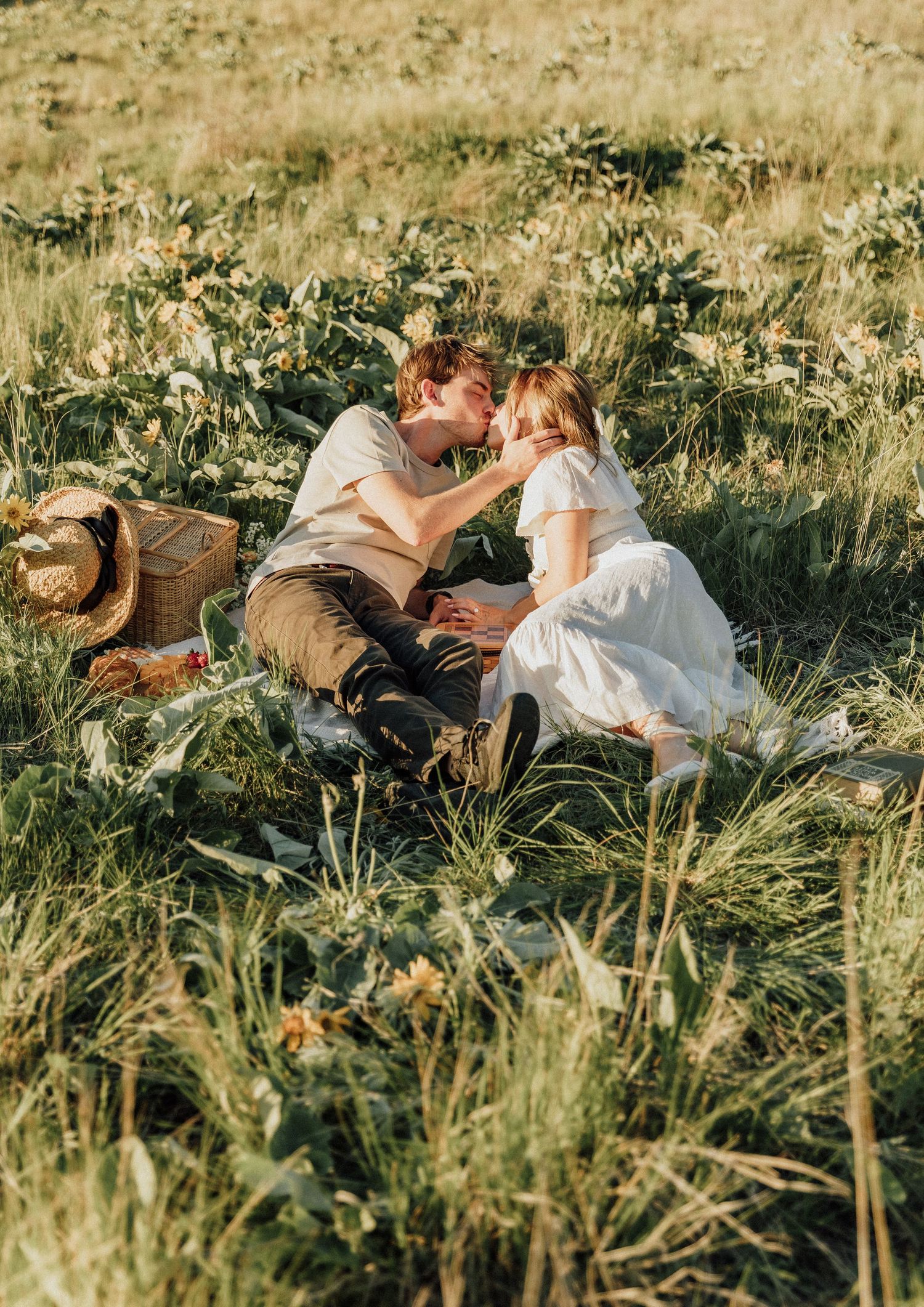 A romantic picnic scene in a wildflower meadow with a straw hat and blanket.