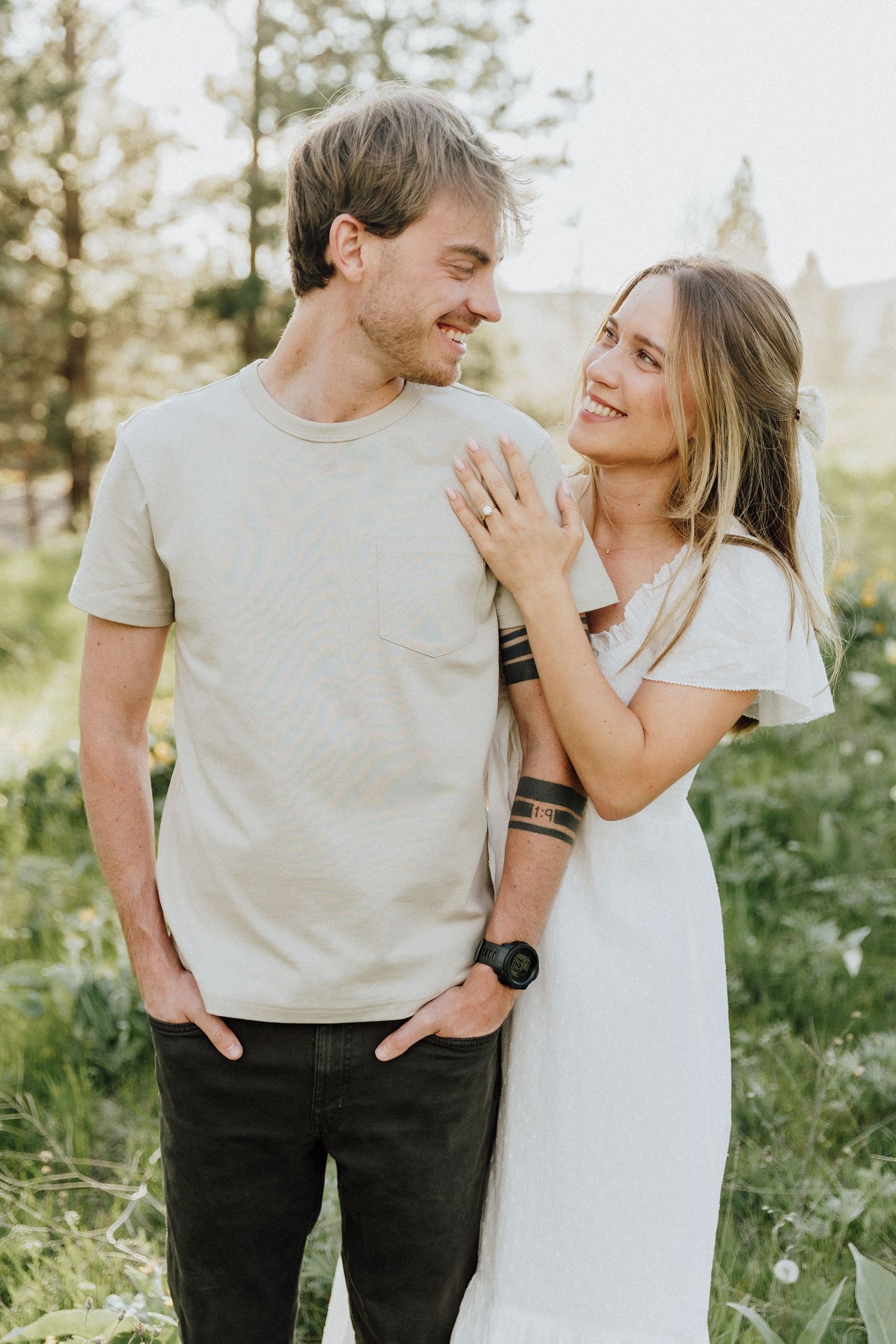 Casual couple in white and beige sharing a joyful moment outdoors.