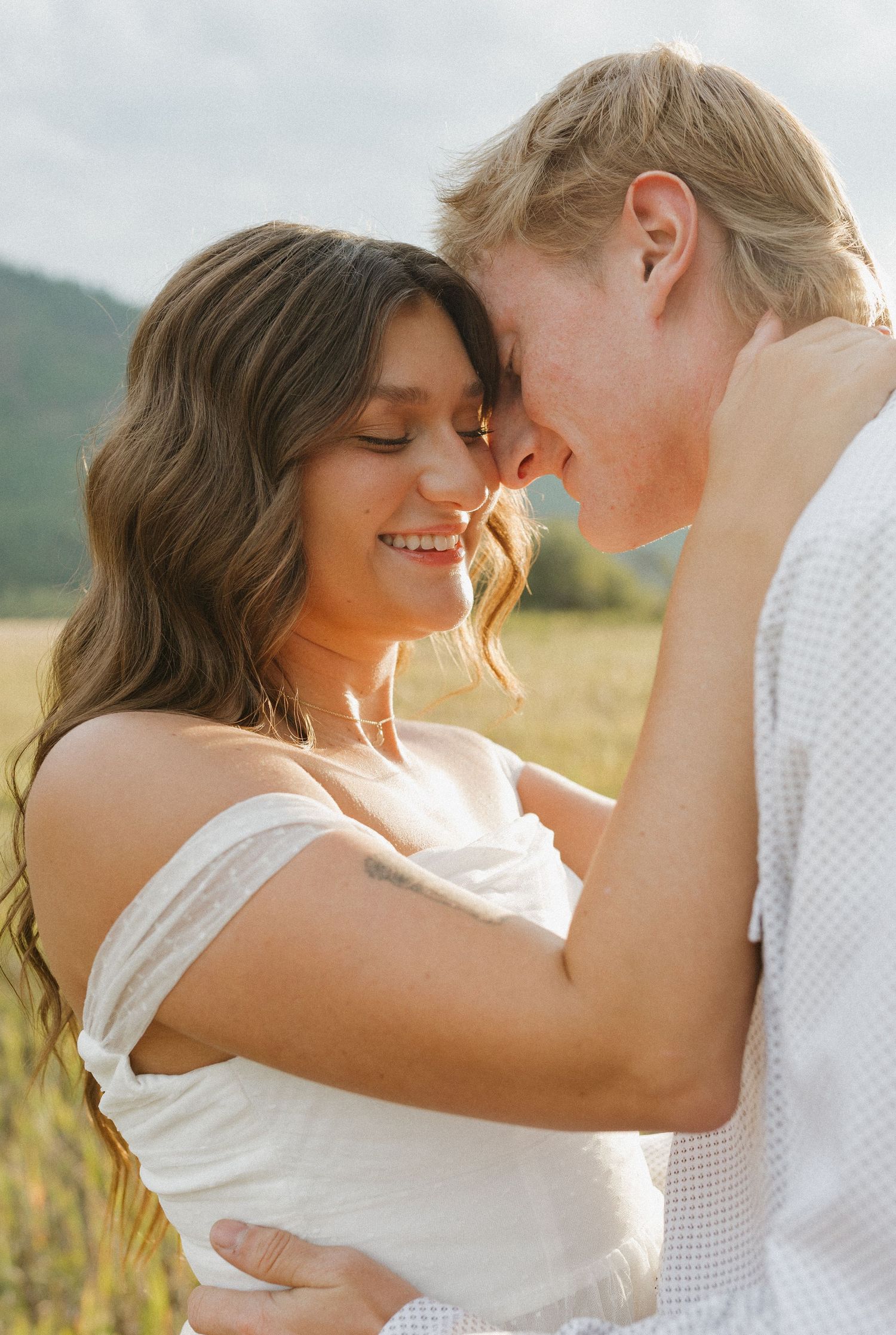 Romantic couple sharing an intimate moment in a golden field at sunset.