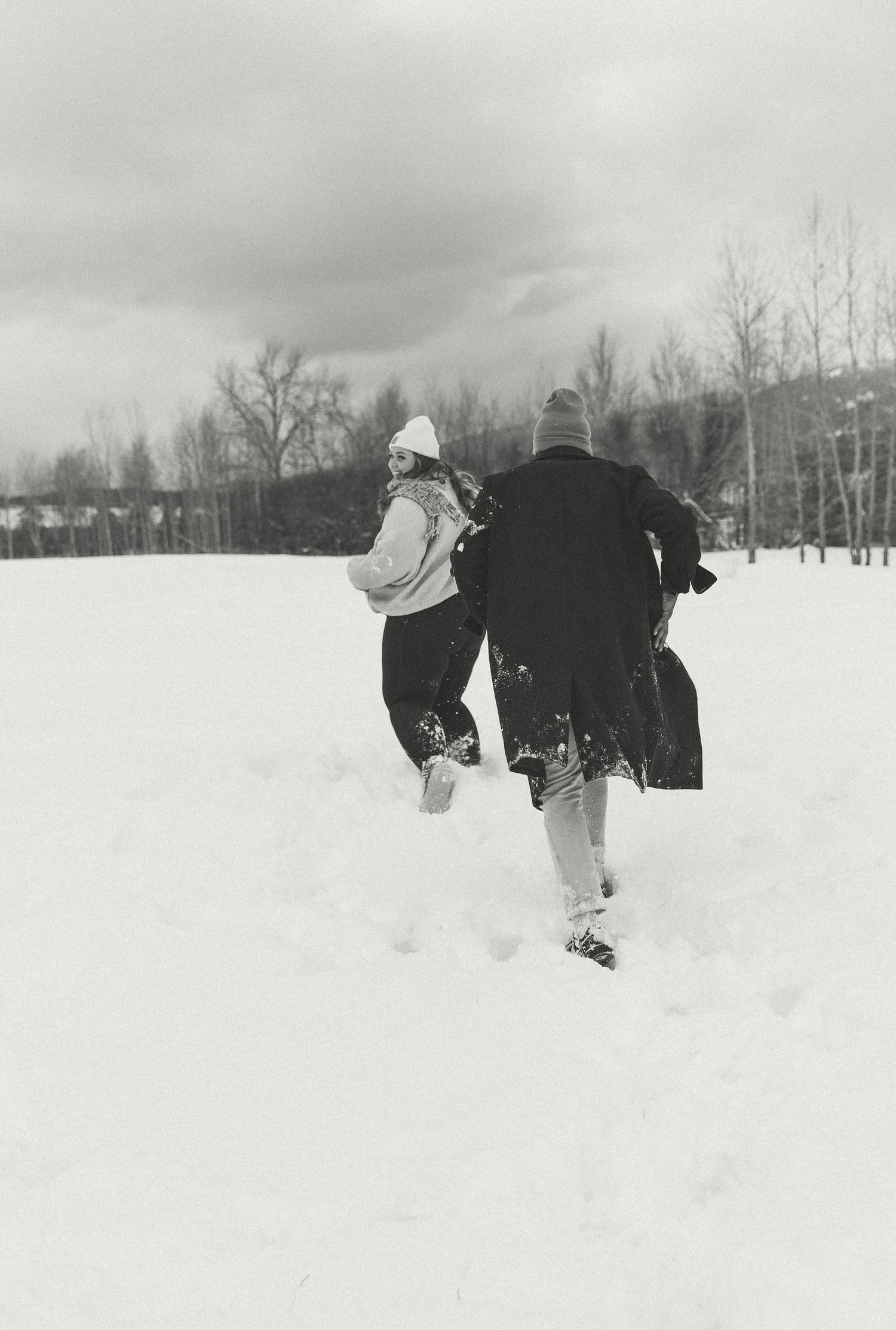 Black and white photo of two people running through deep snow.