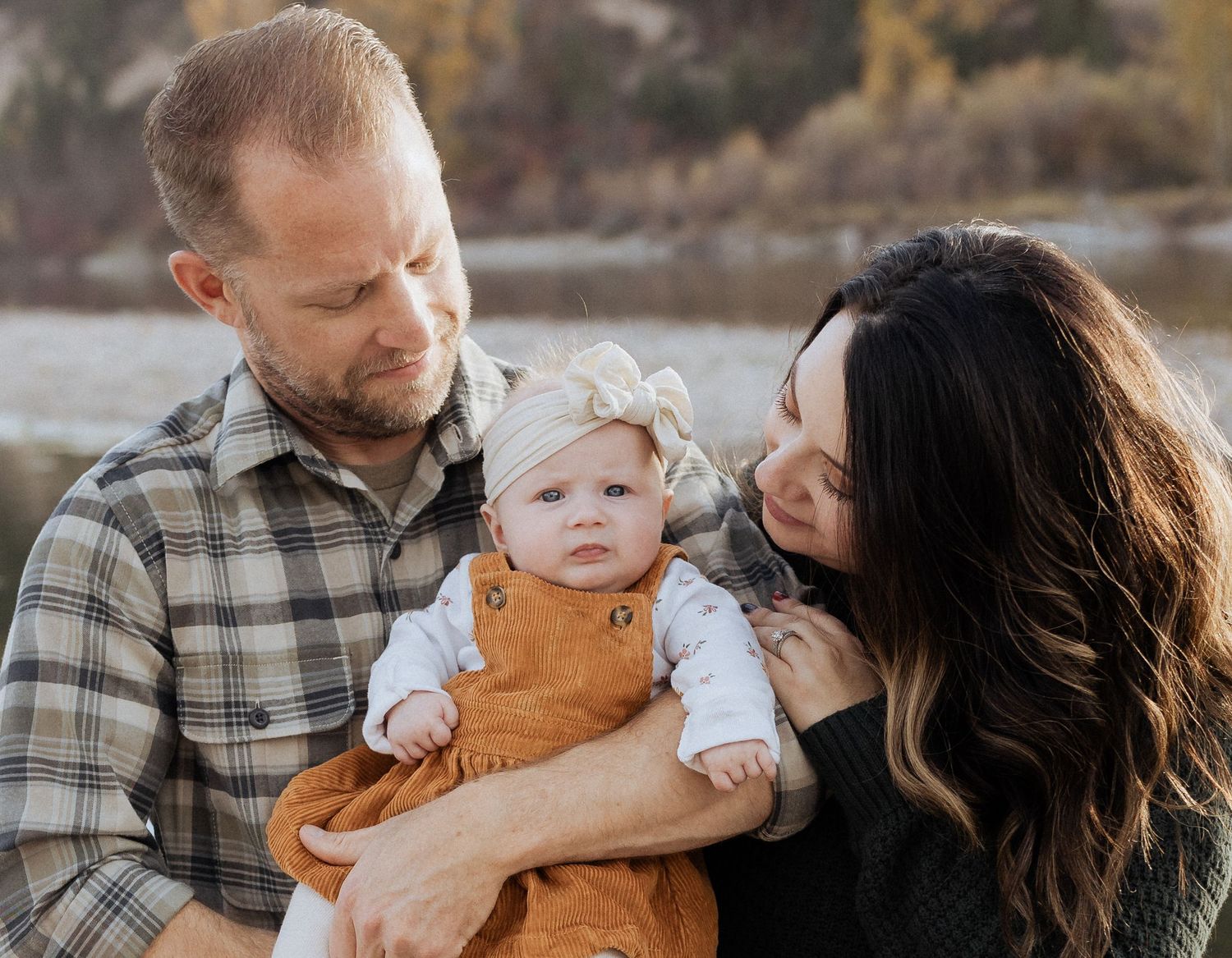Loving family moment captured by lake during golden hour.