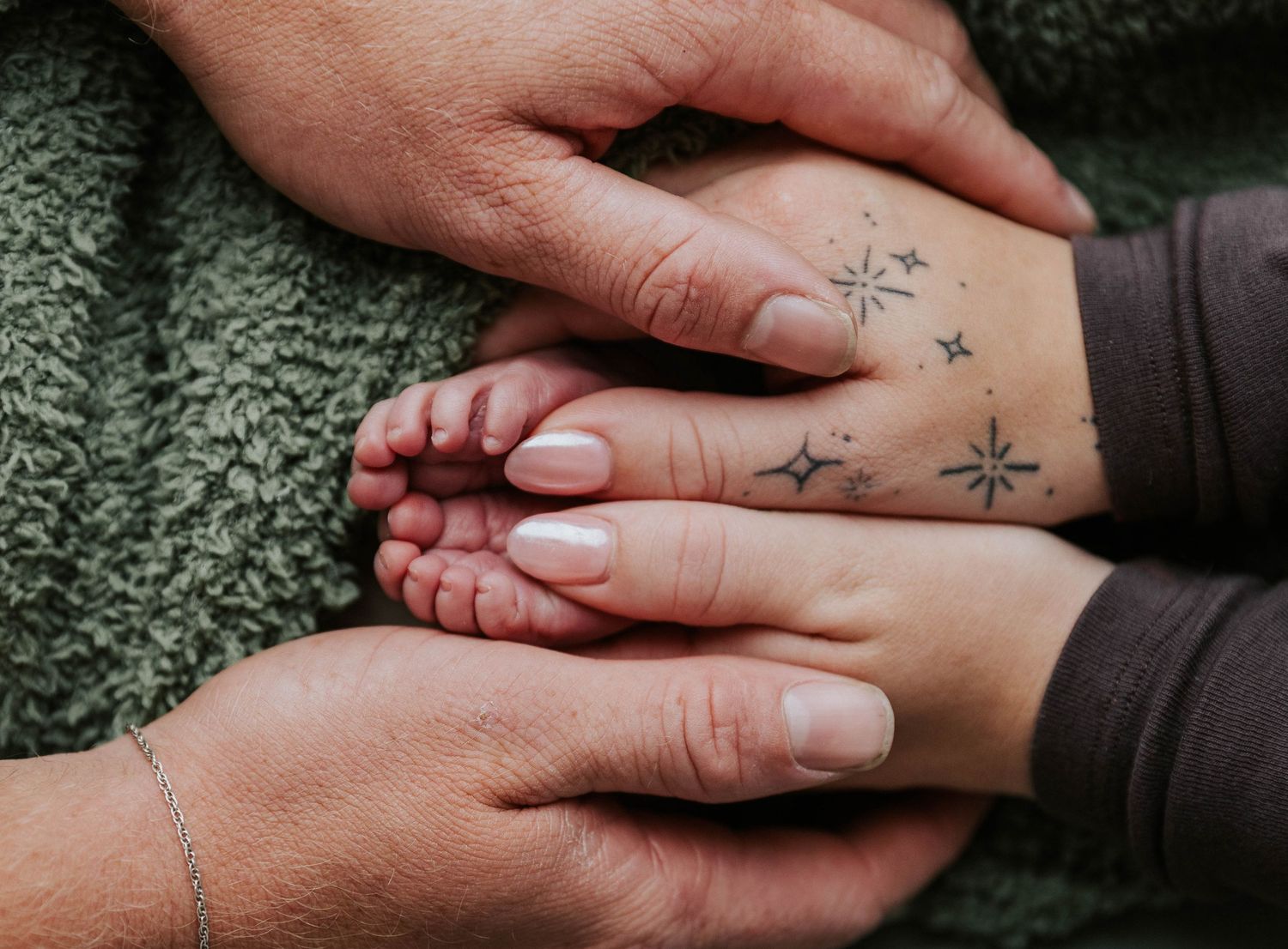 Close-up view of two hands clasped together showing small tattoo symbols on the skin.