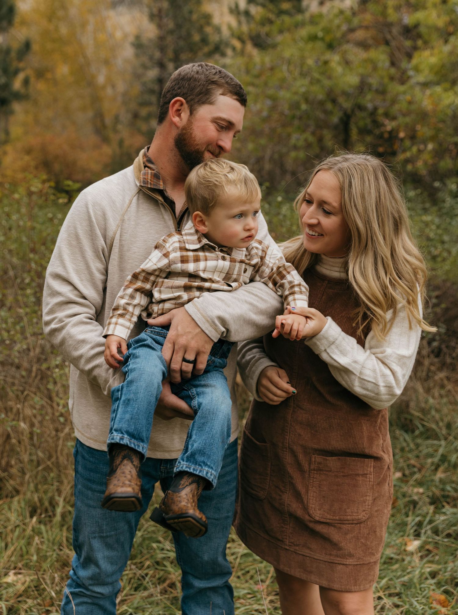 Family shares tender moments together in an autumn outdoor setting wearing coordinated brown and beige outfits.