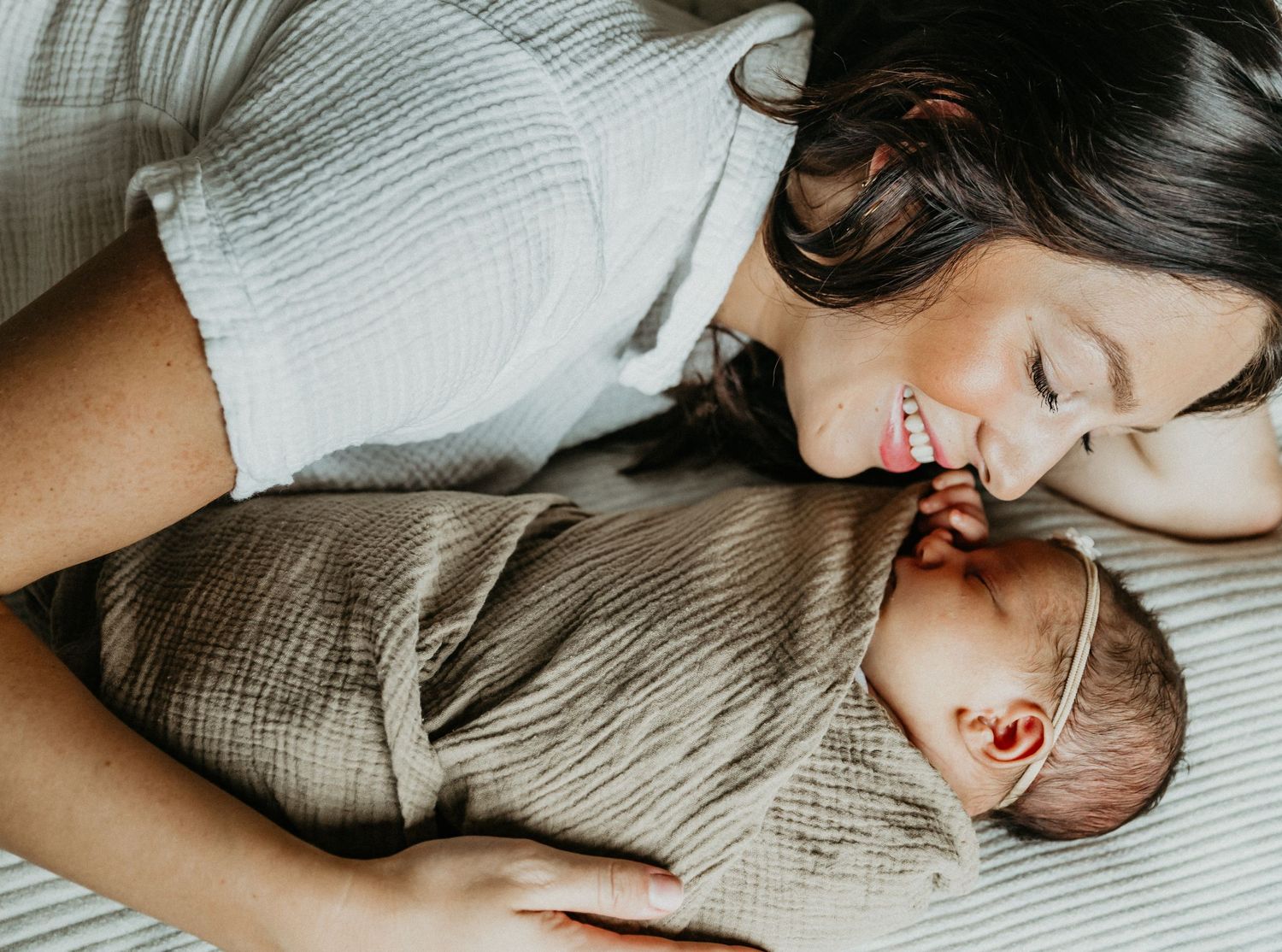 a mother snuggles her newborn in the comfort of her home smiling joyfully