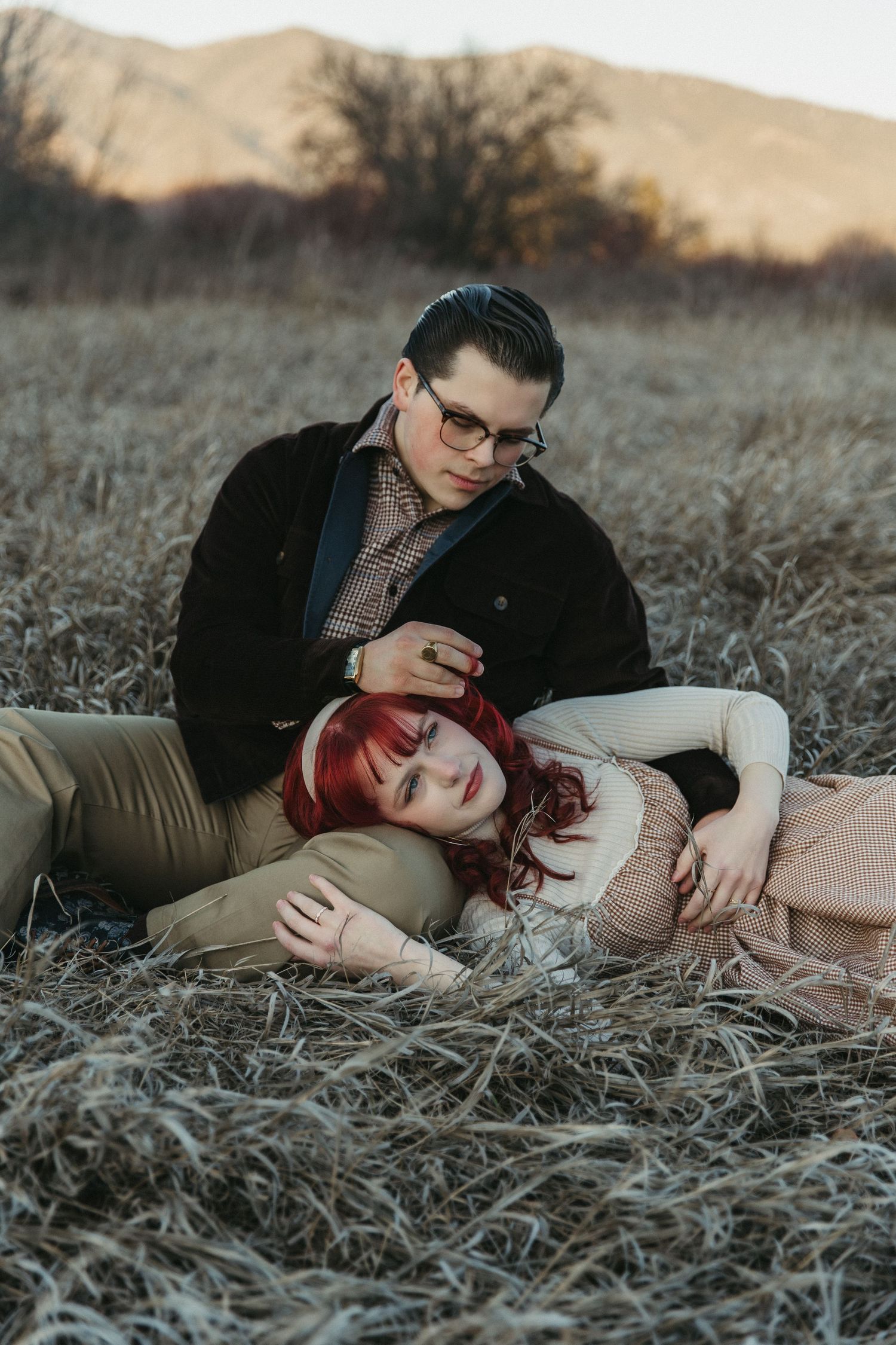 A couple lying in a golden field at sunset share an intimate moment together in a series of romantic photos.