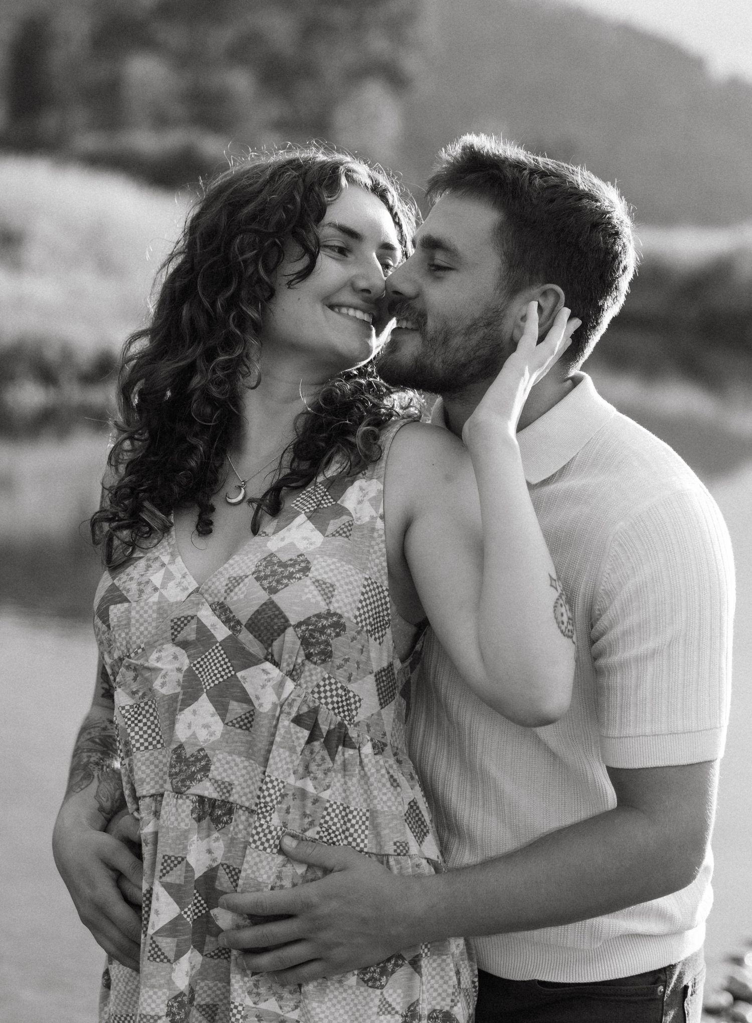 Black and white photo series of romantic couple embracing in floral dress and light shirt outdoors.