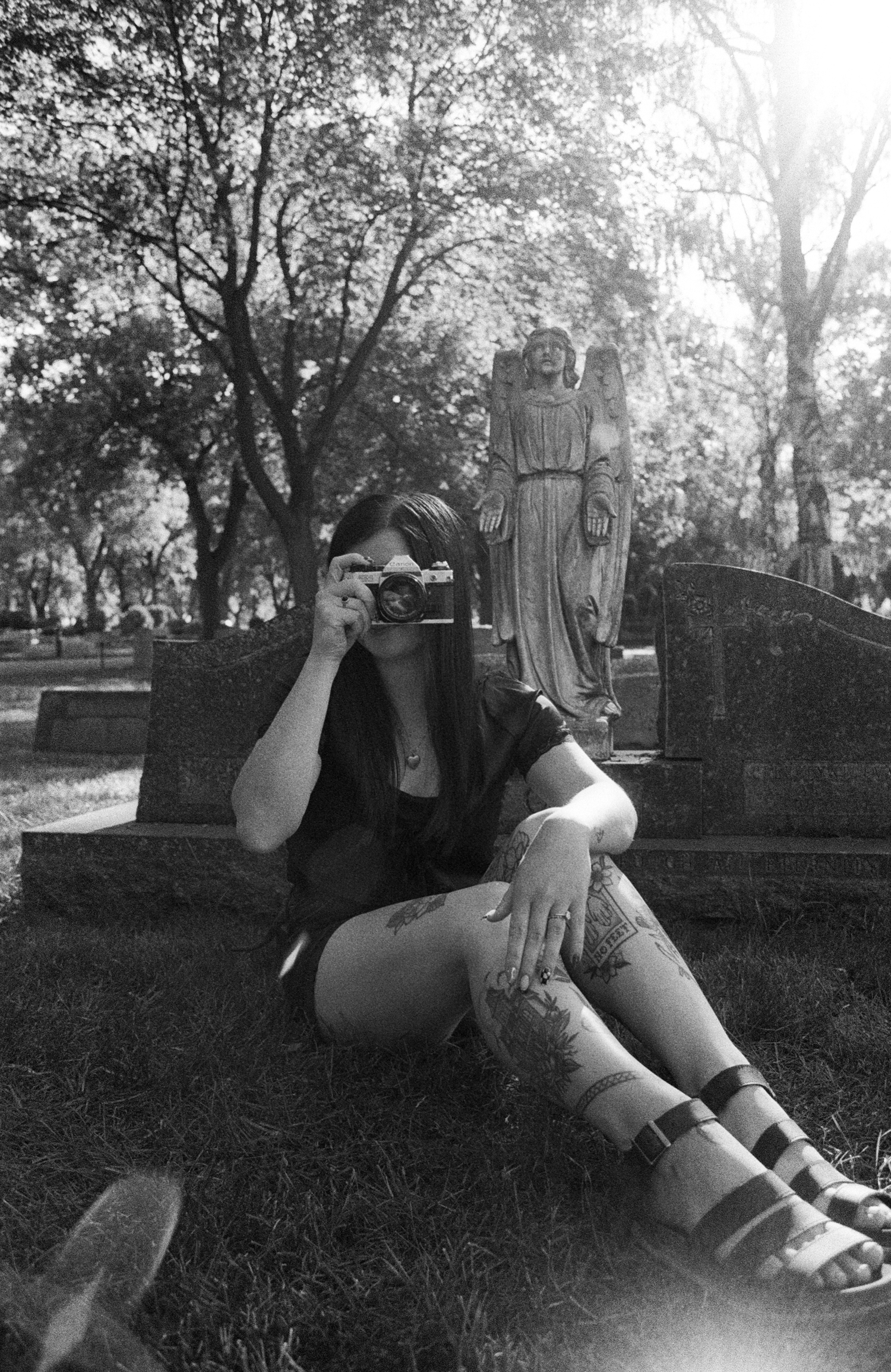 Atmospheric black and white cemetery scene with stone angel statue and Gothic elements among trees.