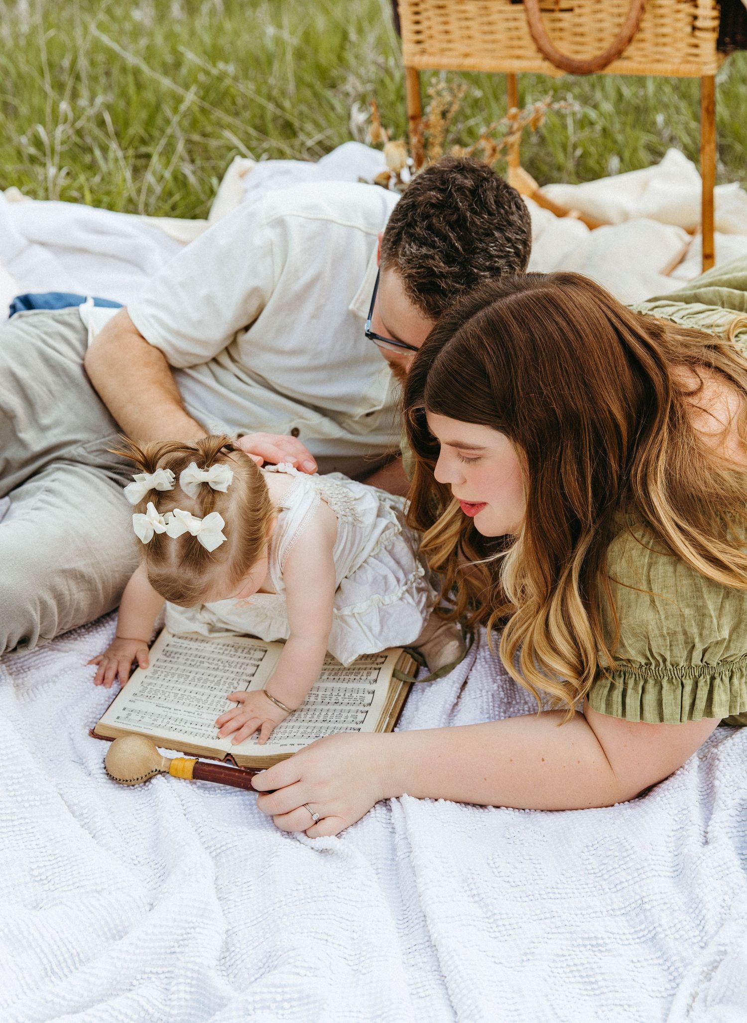 Four sequential shots show someone lying on a blanket reading a book on a sunny day outdoors.