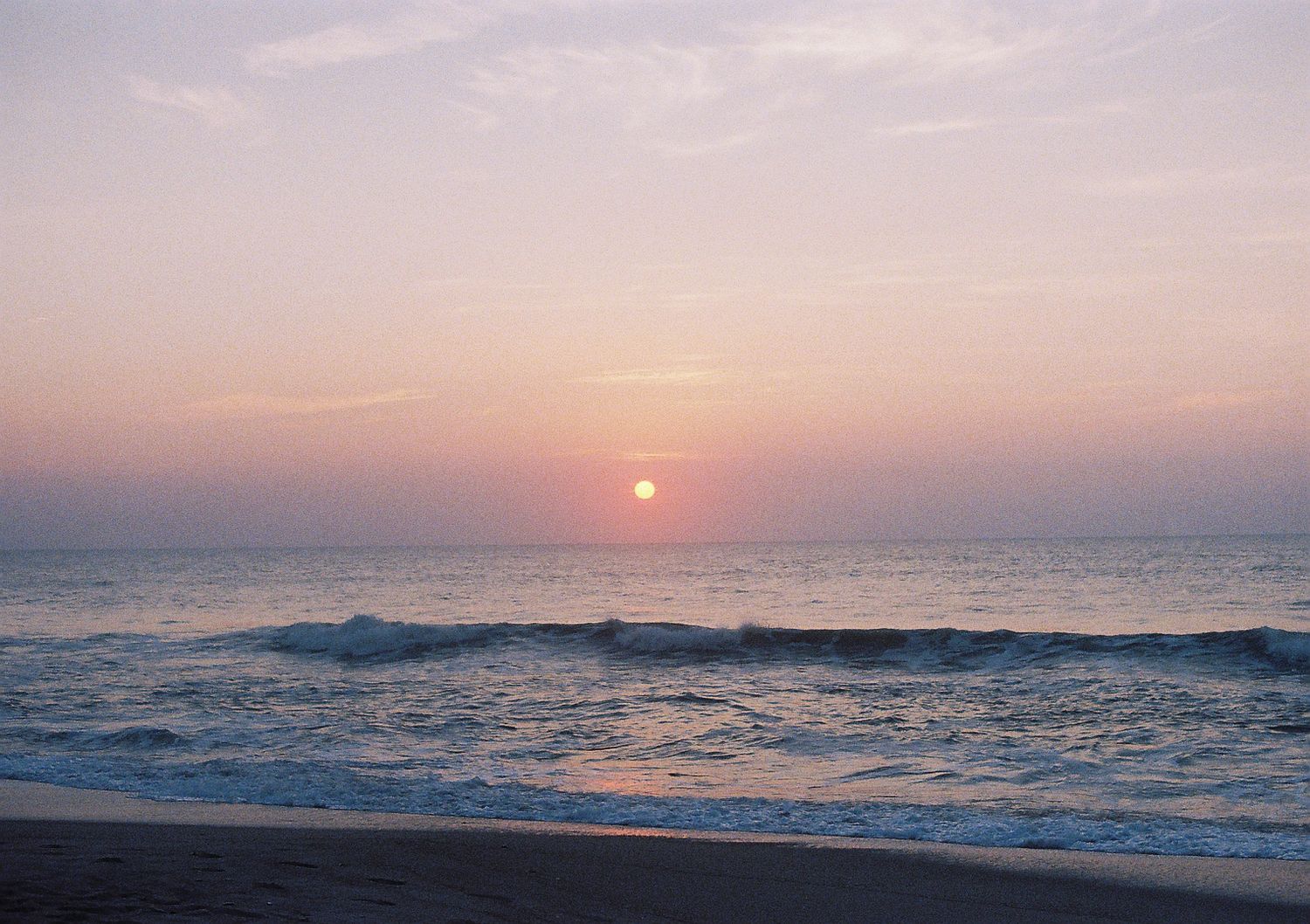 Stunning ocean sunset creates a pink and purple gradient sky over calm waters.