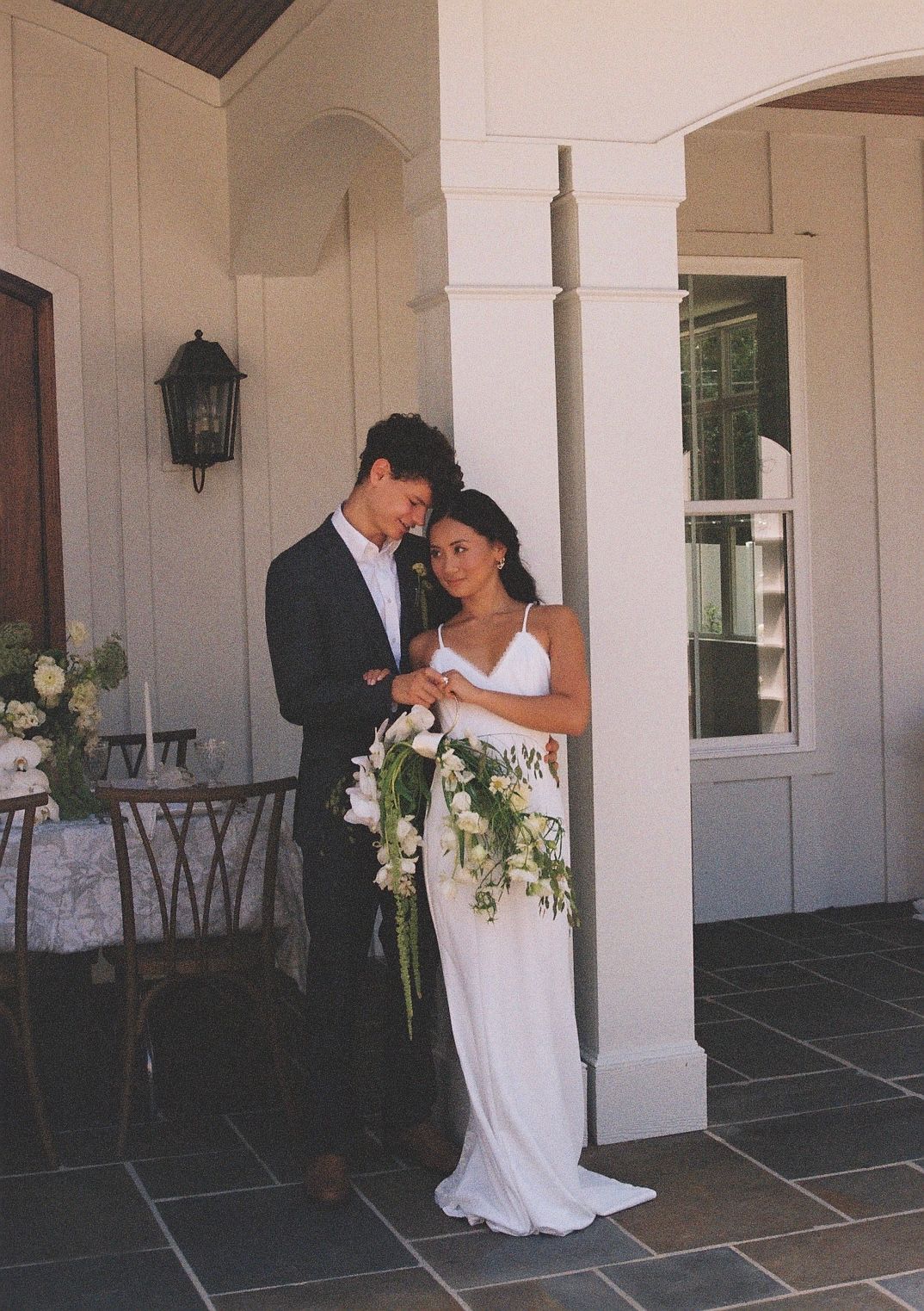 Wedding couple poses under white columns of elegant venue.