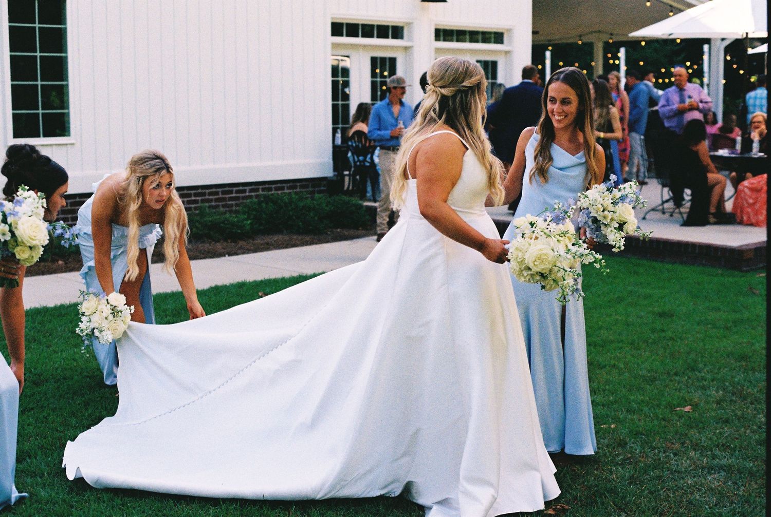 Bridesmaids in pale blue dresses standing in a row outside a white building.