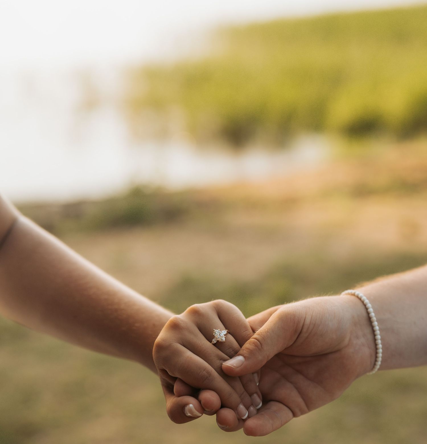 Close-up sequence of hands joining together and showing engagement rings in golden sunlight.
