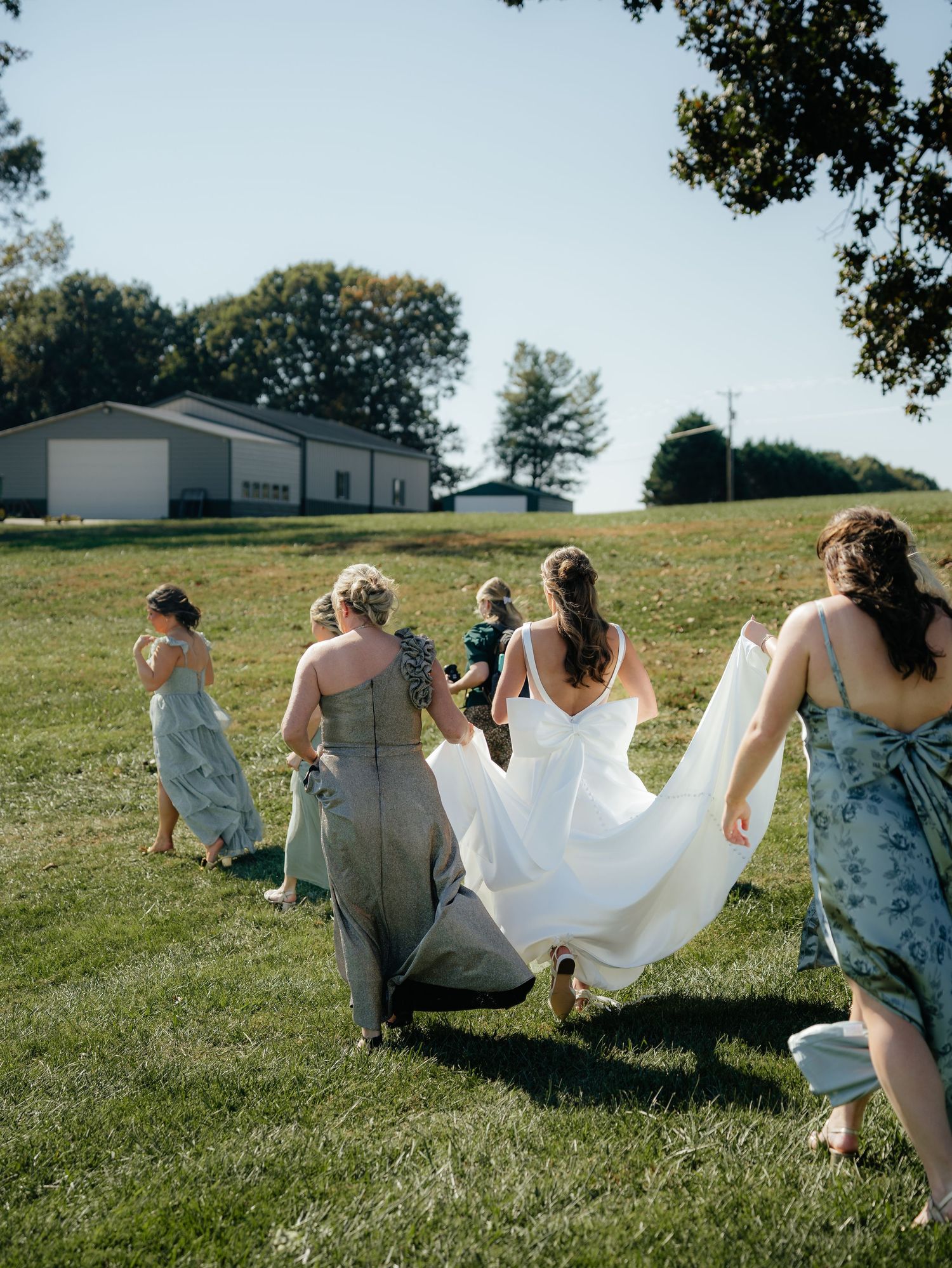 Group of friends sitting together on a grassy hillside enjoying a sunny afternoon outdoors.