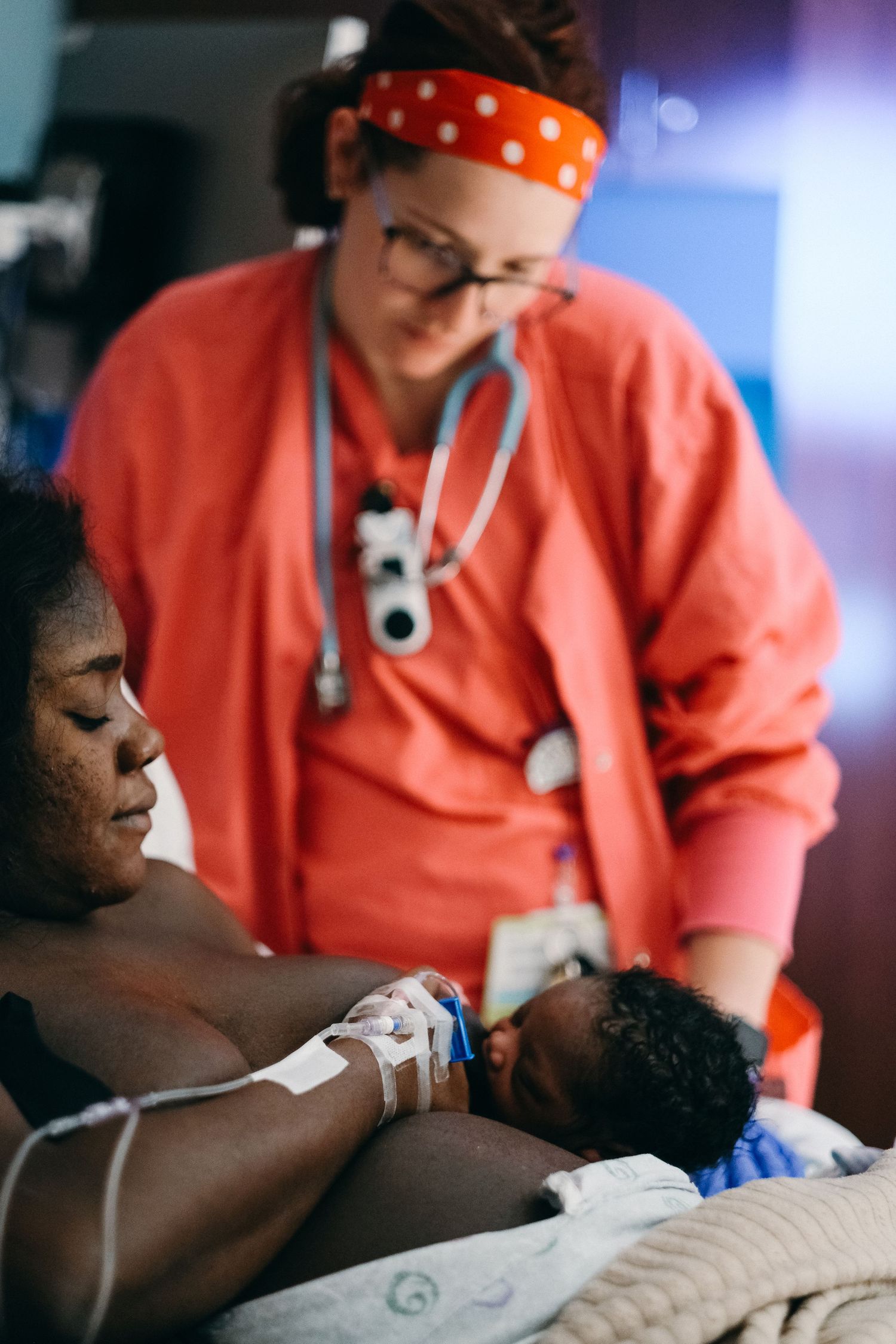 Healthcare workers in orange scrubs provide medical care in a clinical setting.