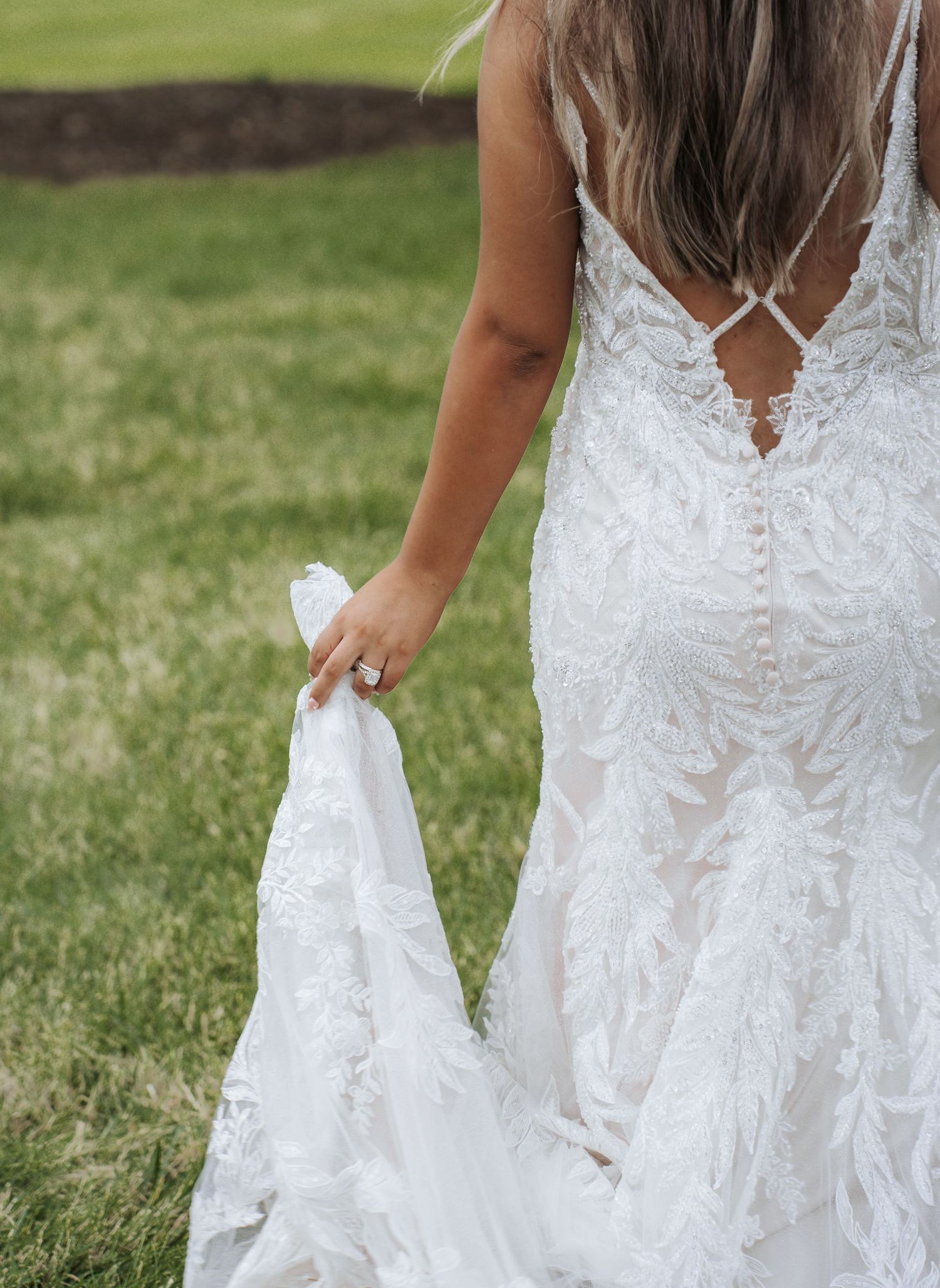 Close-up details of an elegant white lace wedding dress with buttons.
