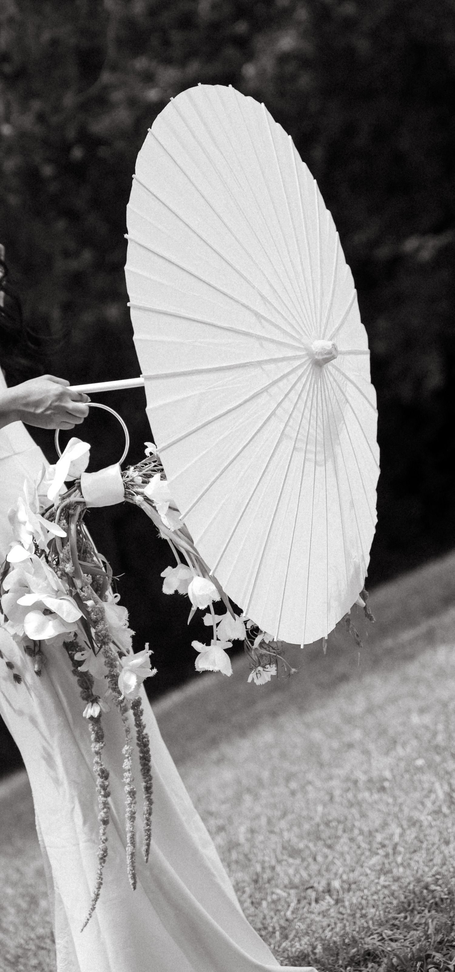 A white paper parasol is held against a dark background in a series of artistic black and white photographs.