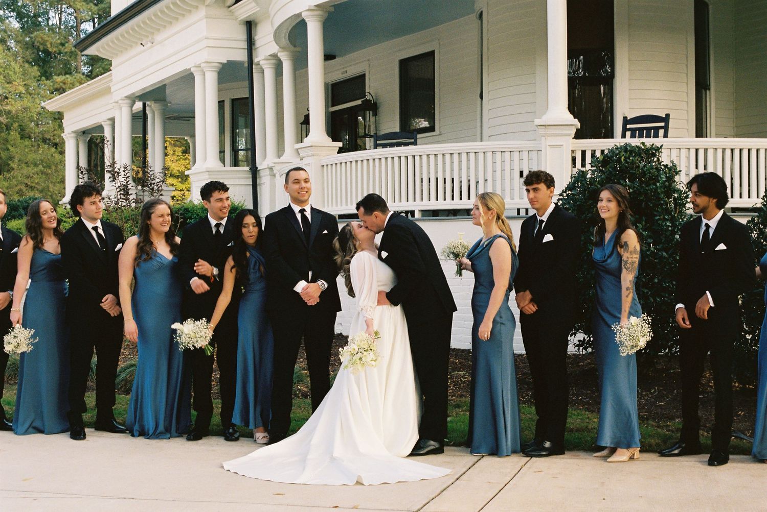Wedding party poses together on the front porch of the elegant Carolina Manor House.