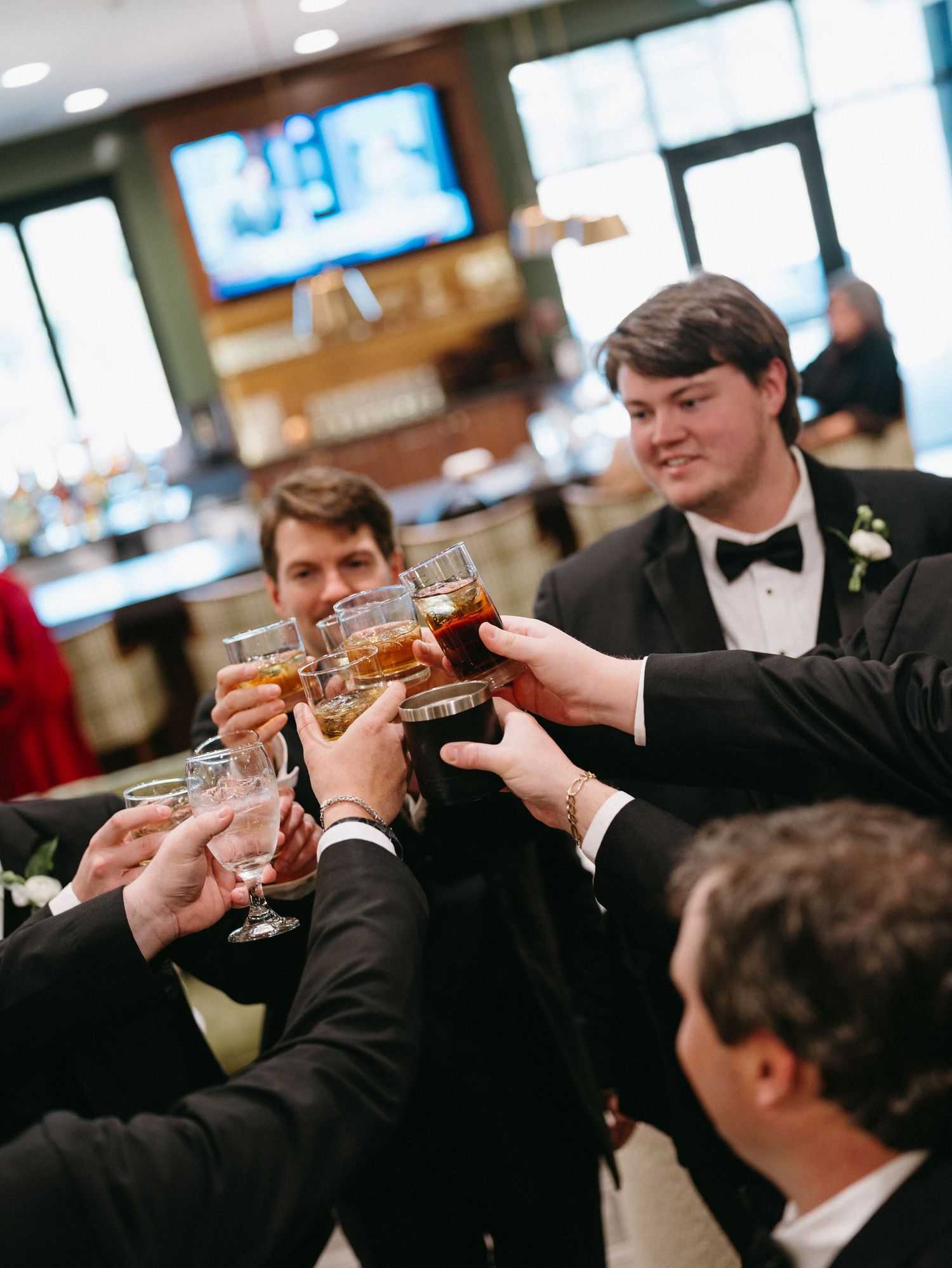 A group of formally dressed guests raise their glasses in a toast during a celebration event.