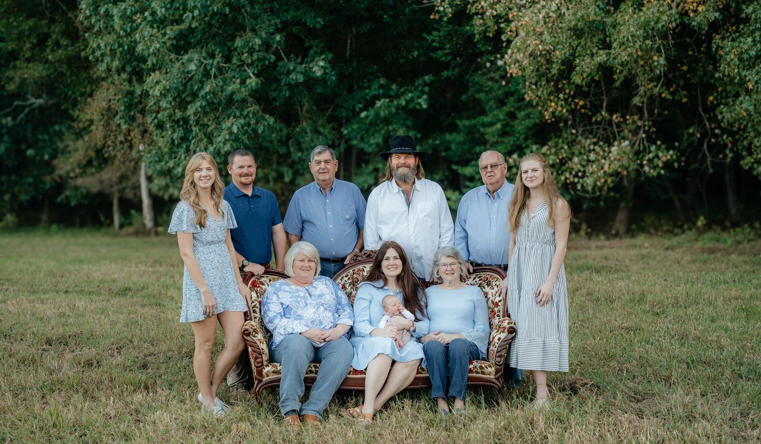 Family portrait session outdoors with vintage furniture and coordinated blue outfits.