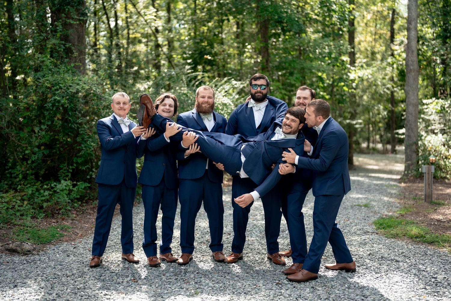Groomsmen in navy suits posing casually outdoors for wedding photos.