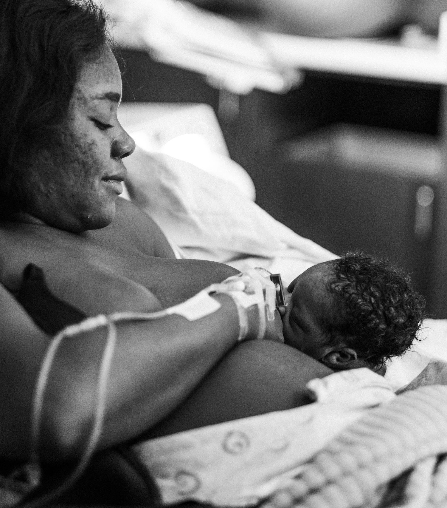 Black and white image of a patient receiving medical treatment in a hospital bed.